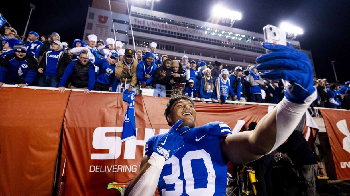 BYU running back Sione I Moa (30) takes a selfie with fans after the Brigham Young University Cougars defeated the University of Utah Utes 22-21 at Rice-Eccles Stadium in Salt Lake City early on Sunday, Nov. 10, 2024.