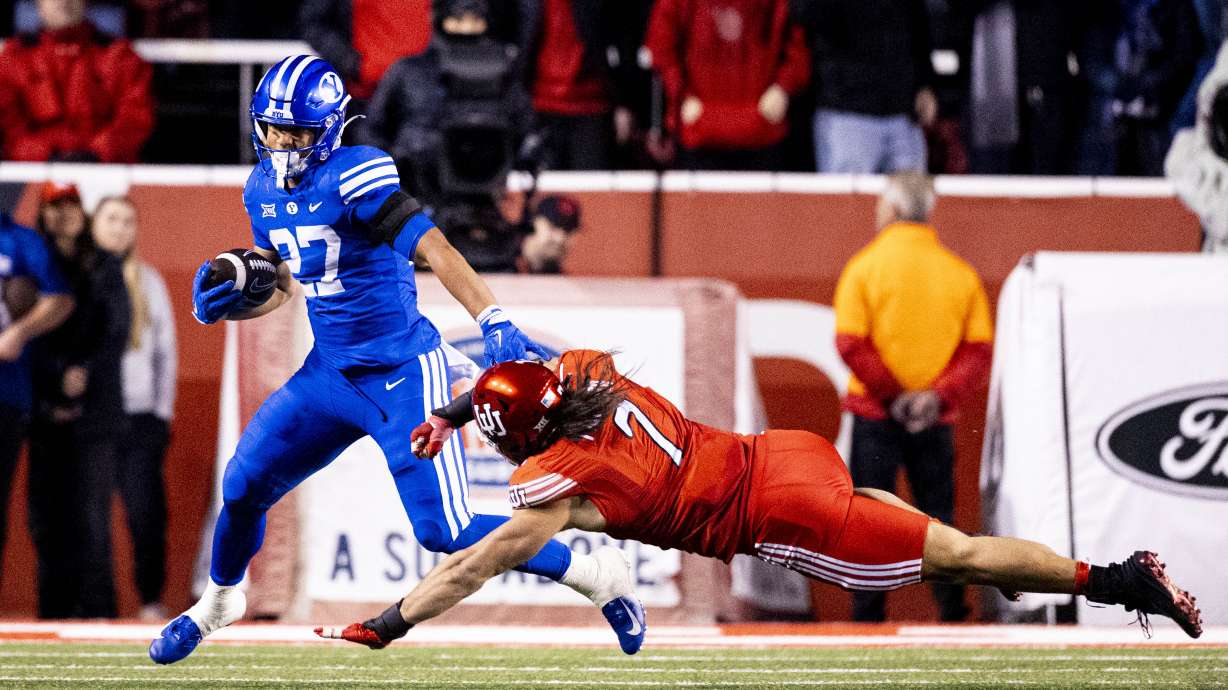 BYU running back LJ Martin (27) evades Utah Utes defensive end Van Fillinger (7) during a game between the University of Utah Utes and the BYU Cougars held at Rice-Eccles Stadium in Salt Lake City on Saturday, Nov. 9, 2024.