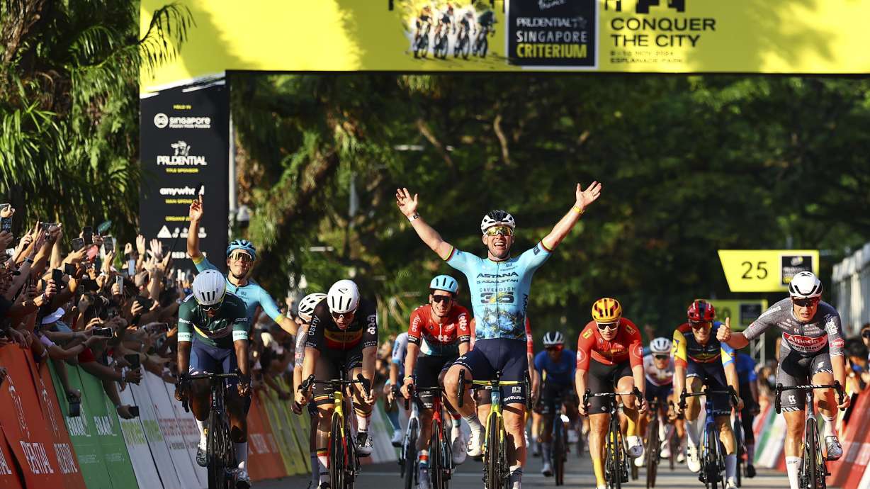 Mark Cavendish of Astana Qazaqstan, centre, celebrates after crossing the finish line during the Prudential Singapore Tour De France Criterium, Sunday, Nov. 10, 2024.