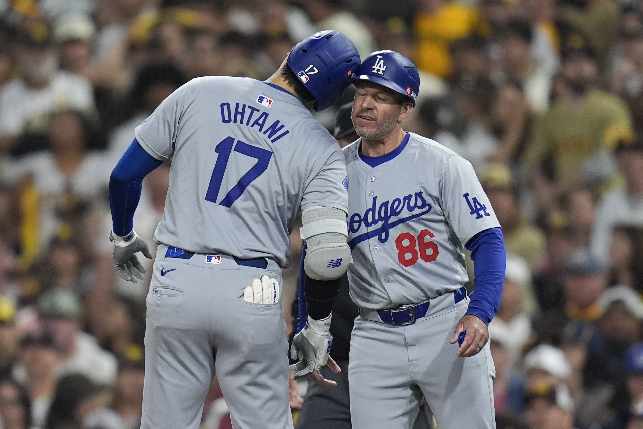 FILE - Los Angeles Dodgers' Shohei Ohtani (17) celebrates with first base coach Clayton McCullough (86) after an RBI single during the second inning in Game 4 of a baseball NL Division Series against the San Diego Padres, Oct. 9, 2024, in San Diego.