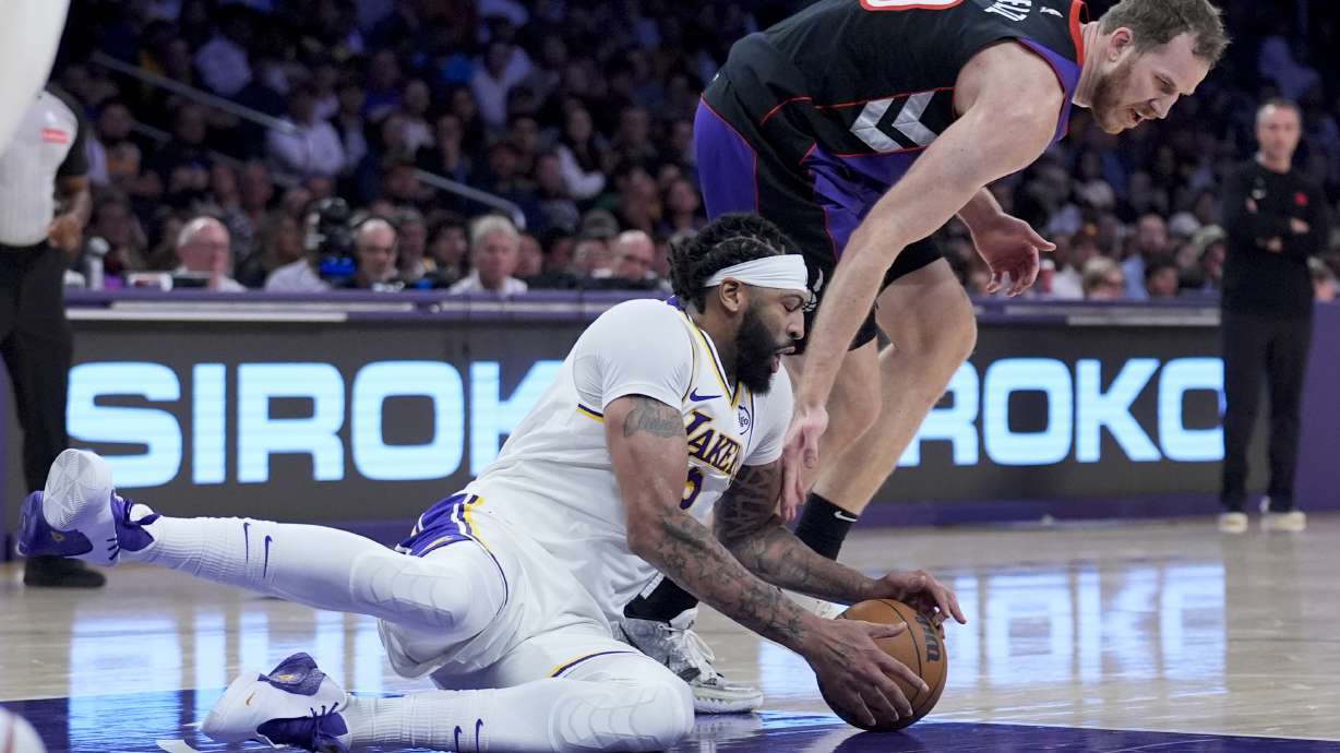 Los Angeles Lakers forward Anthony Davis, left, grabs a loose ball next to Toronto Raptors center Jakob Poeltl during the first half of an NBA basketball game Sunday, Nov. 10, 2024, in Los Angeles.