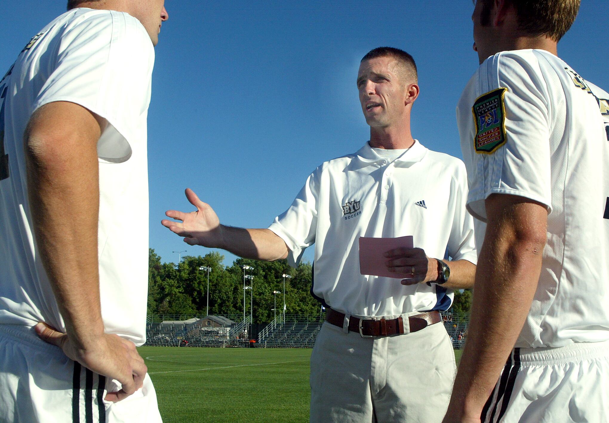 BYU soccer coach Chris Watkins talks with his players Matt Affleck (left) and Matt Walker prior to their game with Fresno State, June 7, 2003.