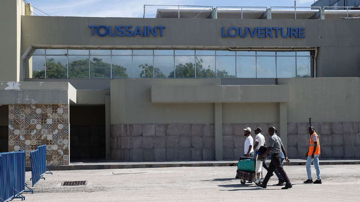 Travelers walk in front of the Toussaint Louverture International Airport in Port-au-Prince in May. Two jets from U.S.-based airlines were struck by bullets on Monday while flying over Port-au-Prince.