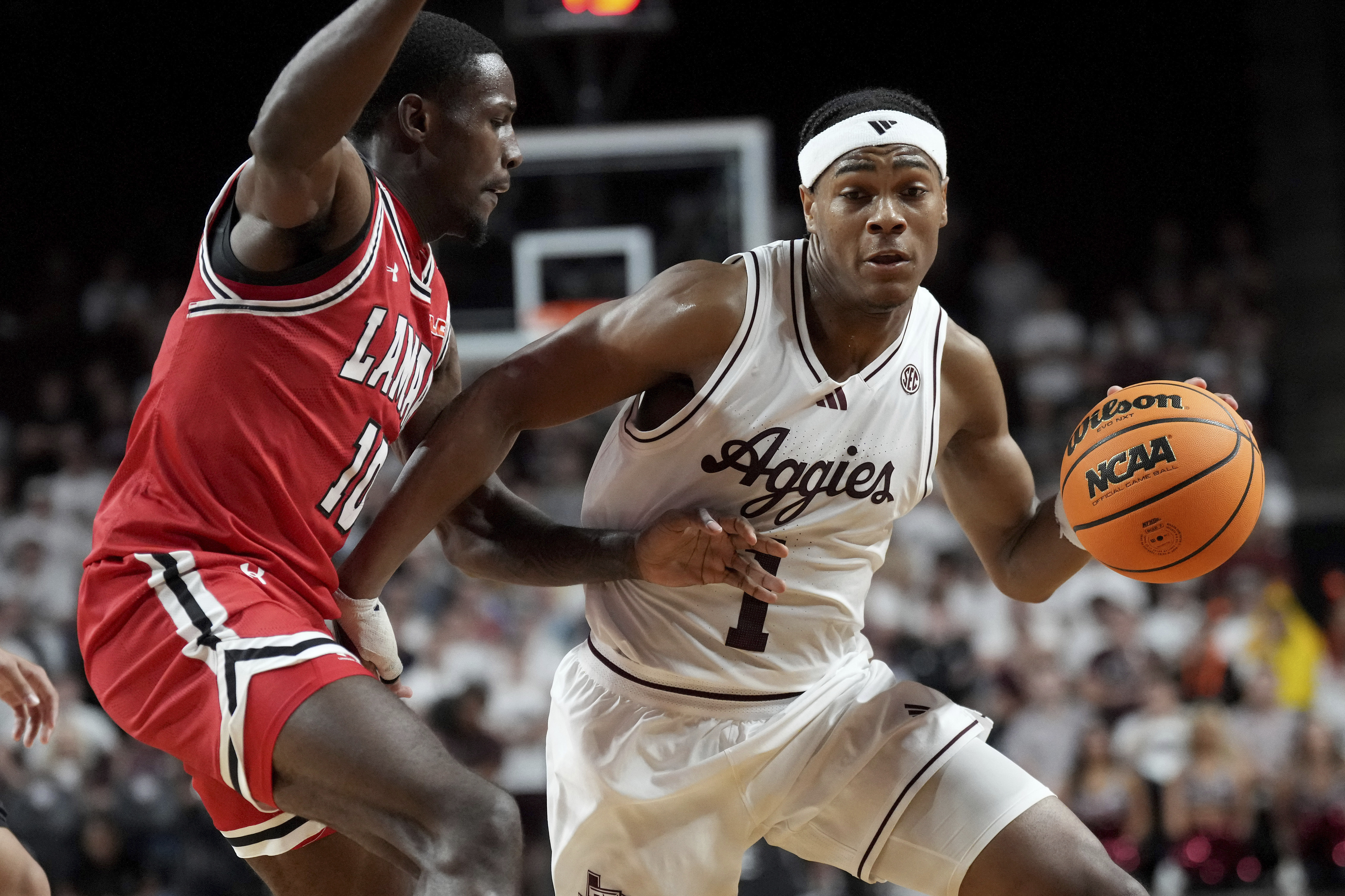 Texas A&M guard Zhuric Phelps (1) drives the lane against Lamar forward Errol White (10) during the first half of an NCAA college basketball game, Monday, Nov. 11, 2024, in College Station, Texas.