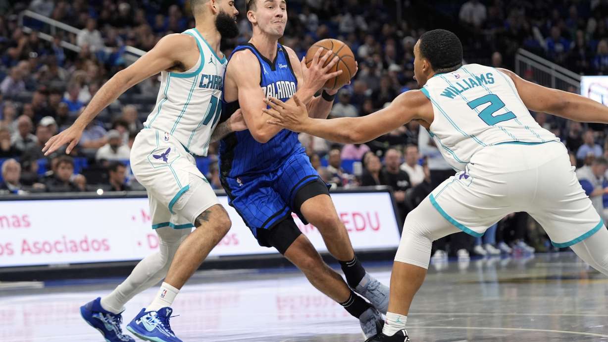 Orlando Magic forward Franz Wagner, center, drives between Charlotte Hornets forward Cody Martin, left, and forward Grant Williams (2) during the second half of an Emirates NBA Cup basketball game, Tuesday, Nov. 12, 2024, in Orlando, Fla.