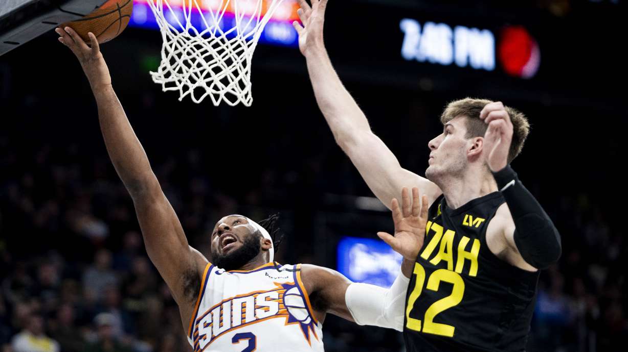 Phoenix Suns forward Josh Okogie (2) lays the ball up while guarded by Utah Jazz forward Kyle Filipowski (22) during an NBA basketball game held at the Delta Center in Salt Lake City on Tuesday, Nov. 12, 2024.