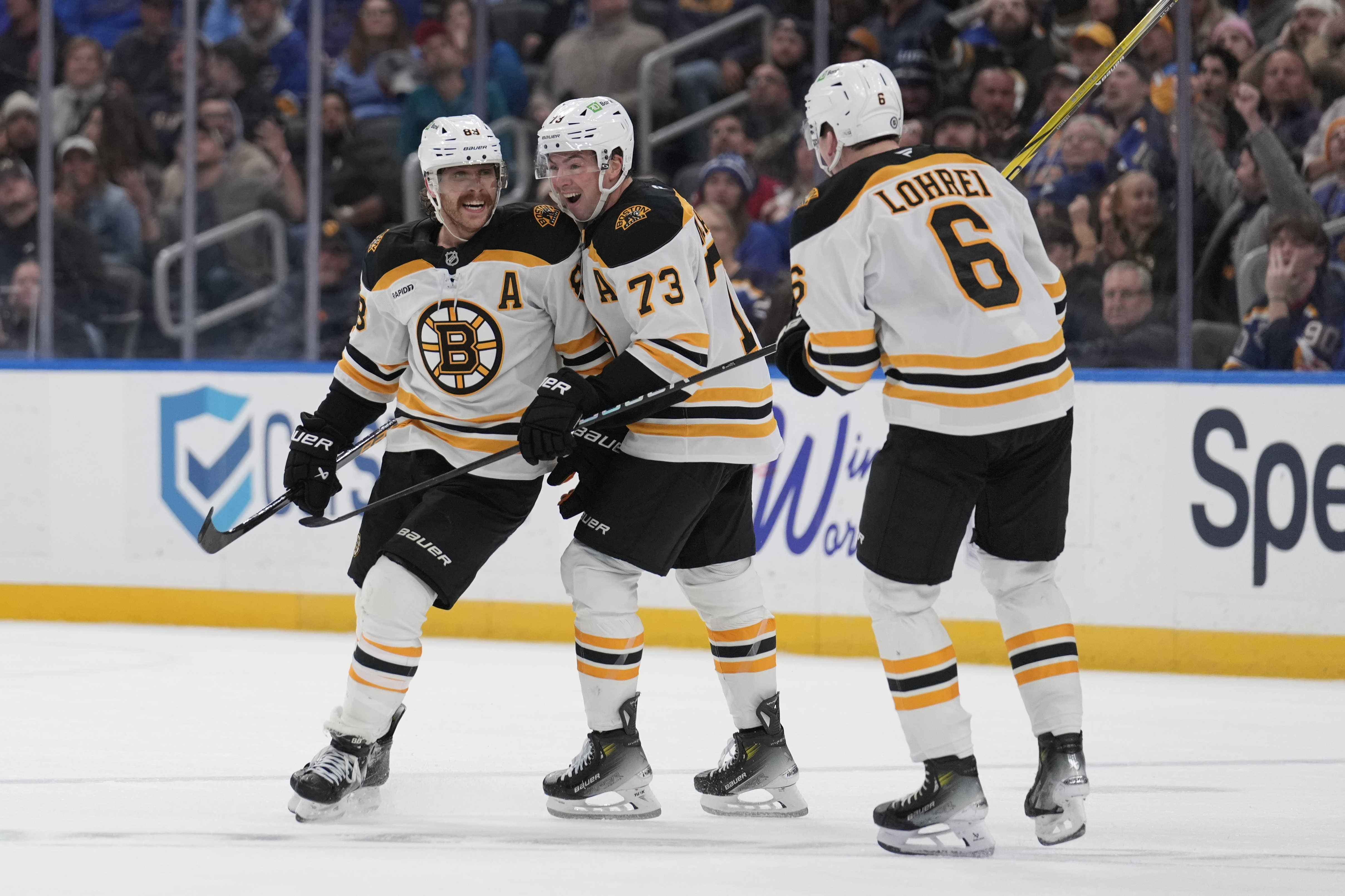 Boston Bruins' David Pastrnak, left, is congratulated by Charlie McAvoy (73) and Mason Lohrei (6) after scoring during the third period of an NHL hockey game against the St. Louis Blues Tuesday, Nov. 12, 2024, in St. Louis.