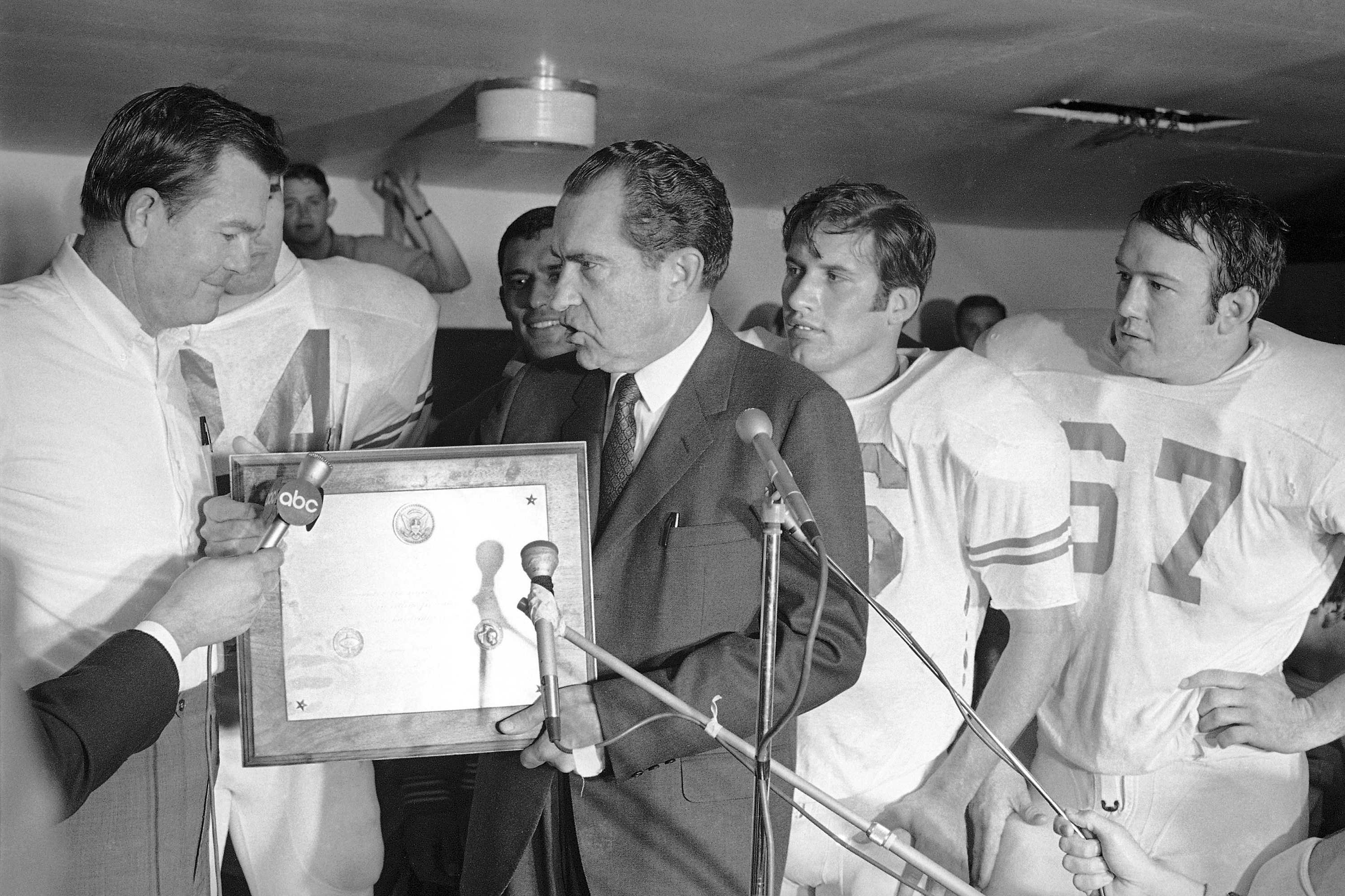 FILE - President Richard Nixon presents a plaque to Texas football coach Darrell Royal, naming the Longhorns the No. 1 college football team in college football as linebacker Glen Halsell (67) and quarterback James Street (16) watch, Dec. 6, 1969.