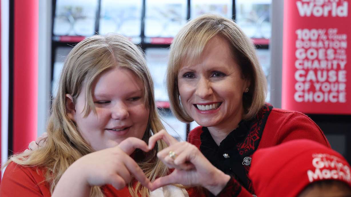 Sister Amy A. Wright, first counselor in the Primary general presidency, makes a heart with Lucy Howcroft during the global launch of the Light the World giving machines at the Conference Center in Salt Lake City on Wednesday.