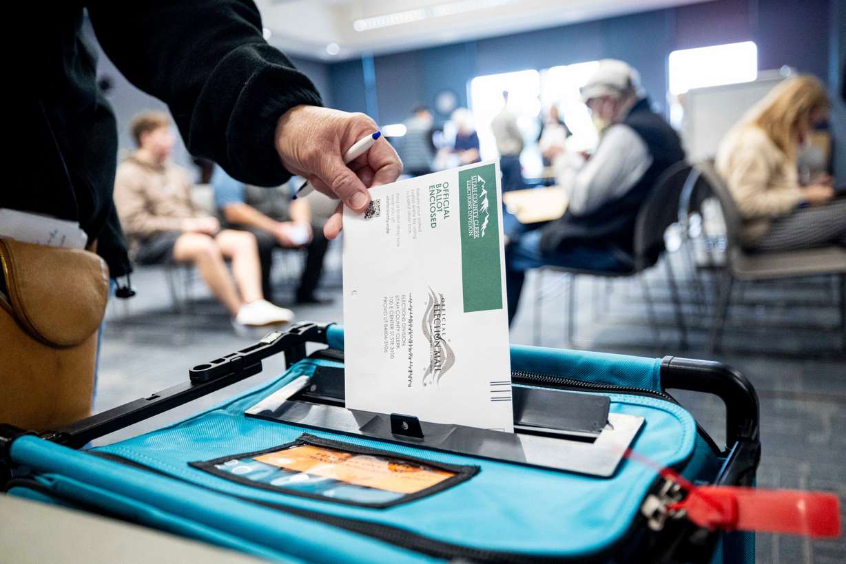 A voter drops a ballot in a drop box during early voting for the upcoming general election held at the Utah County Health and Justice Building in Provo on Oct. 30.