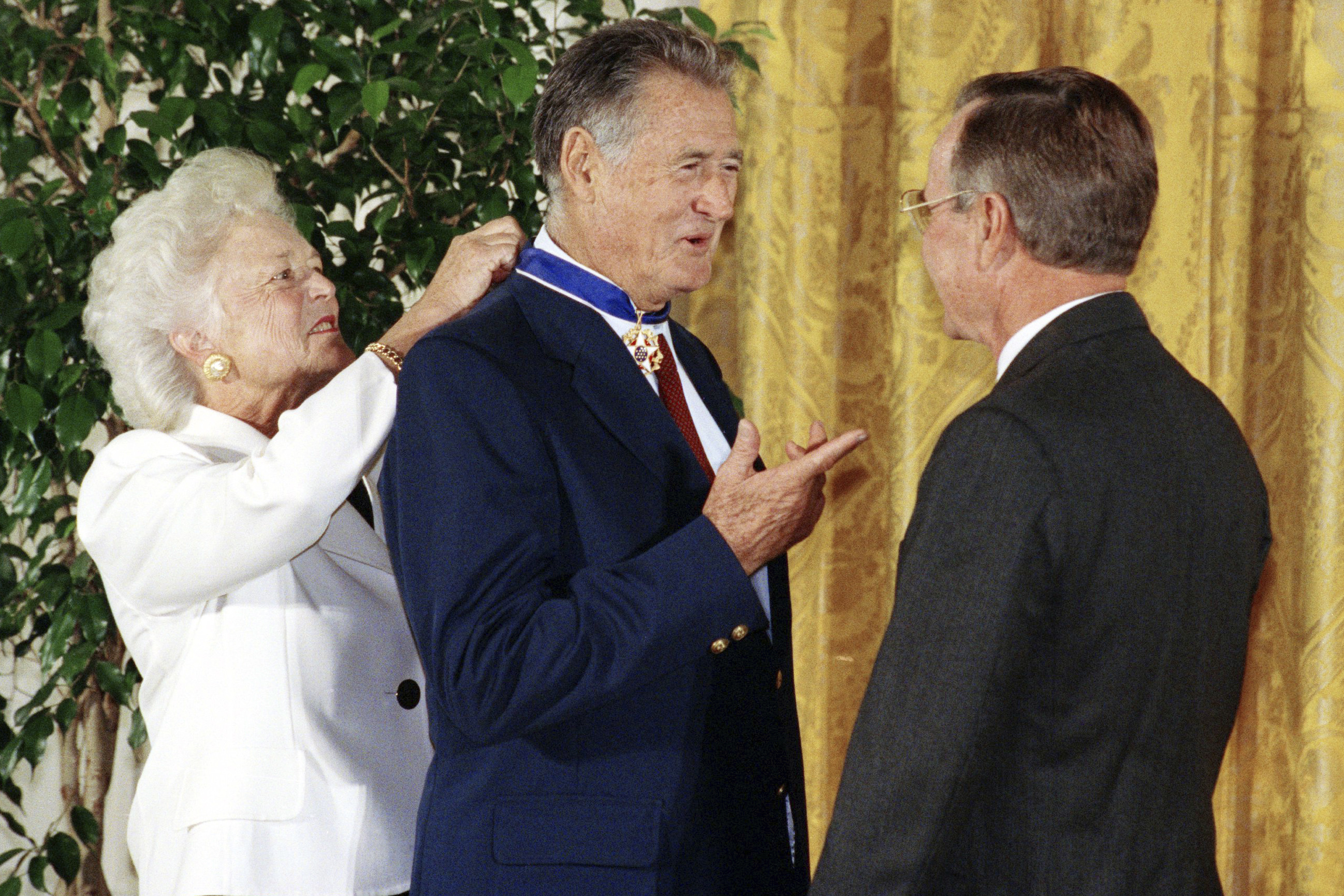 FILE - President George W. Bush, right, presents the Presidential Medal of Freedom to baseball great Ted Williams as Barbara Bush ties the medal around his neck Monday, Nov. 18, 1991, at a White House ceremony in Washington.