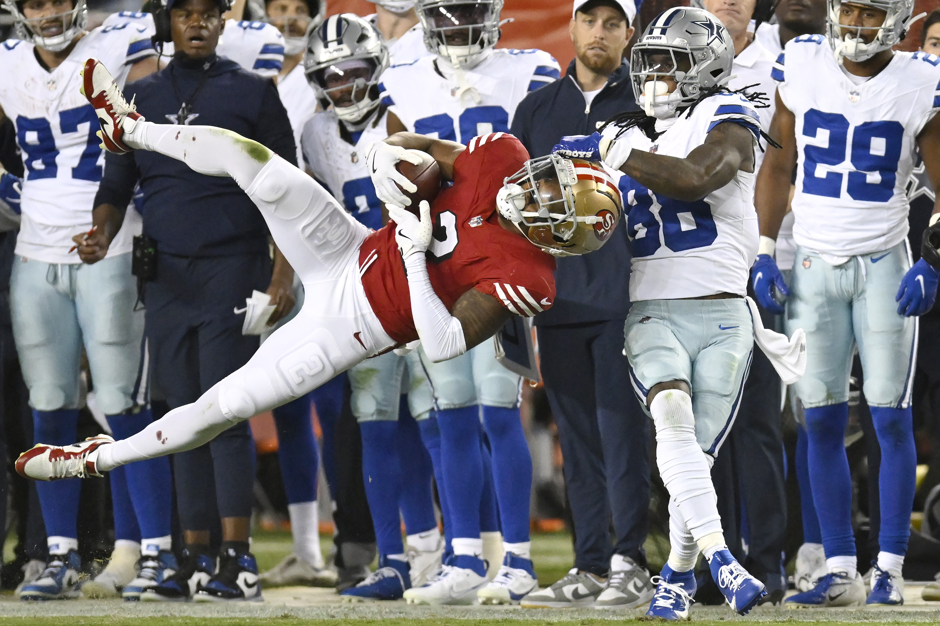 San Francisco 49ers cornerback Deommodore Lenoir, foreground left, intercepts a pass intended for Dallas Cowboys wide receiver CeeDee Lamb (88) during the second half of an NFL football game in Santa Clara, Calif., Sunday, Oct. 27, 2024.