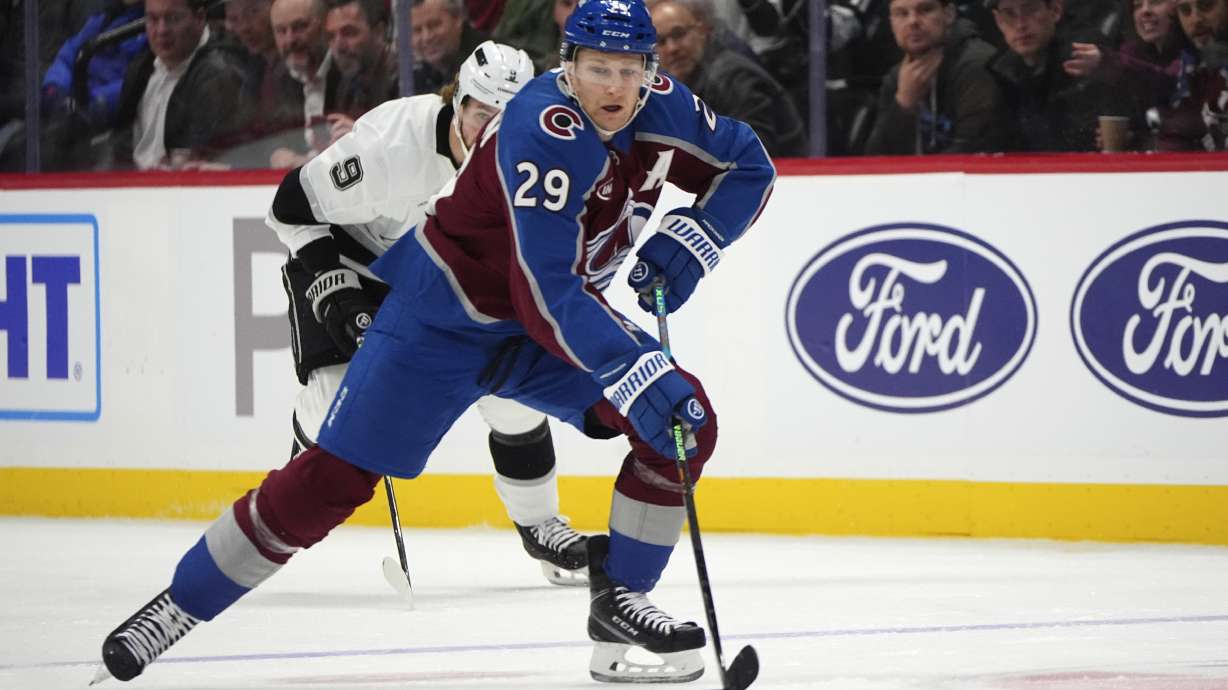 Colorado Avalanche center Nathan MacKinnon, front, collects the puck with Los Angeles Kings right wing Adrian Kempe in pursuit in the first period of an NHL hockey game Wednesday, Nov. 134, 2024, in Denver.