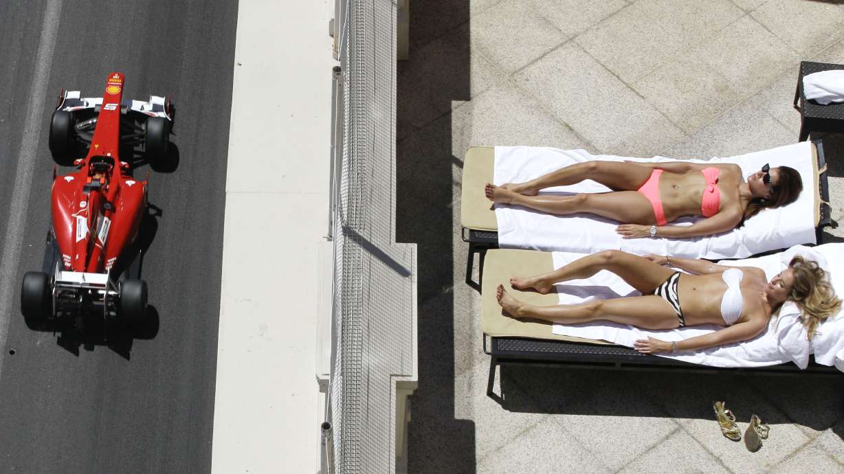 FILE - Ferrari driver Fernando Alonso of Spain steers his car as two sunbathers relaxes on a terrace during the qualifying session at the Monaco racetrack, on May 28, 2011.