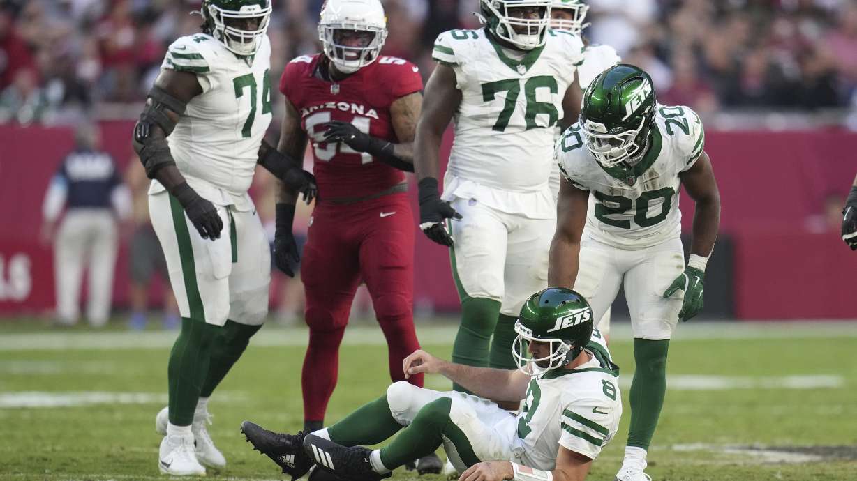 New York Jets quarterback Aaron Rodgers (8) is helped up by running back Breece Hall (20) after taking a sack against the Arizona Cardinals during the second half of an NFL football game, Sunday, Nov. 10, 2024, in Glendale, Ariz.