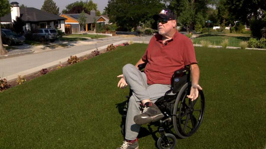 Tony Hughes sits in his wheelchair on his lawn in Salt Lake City in 2024. He said he doesn’t understand why Salt Lake City is forcing him to rip out the artificial turf in his front yard when city, state and federal leaders have asked residents to conserve water.