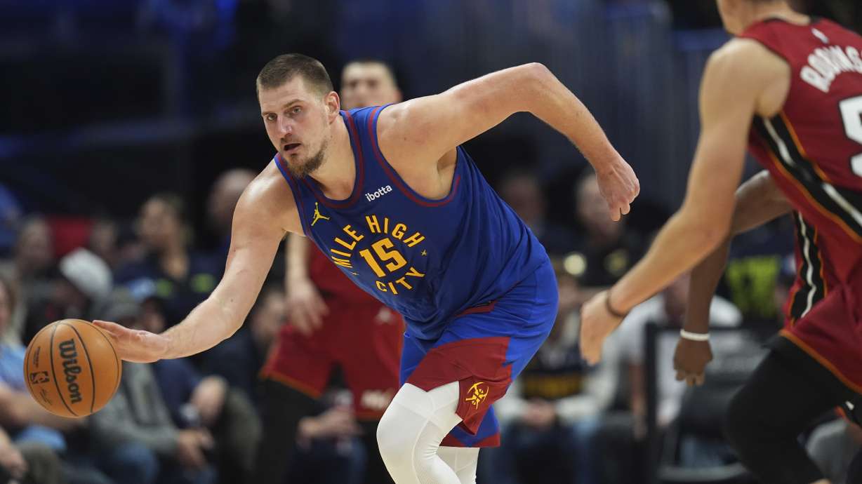 Denver Nuggets center Nikola Jokic, left, collects a loose ball as Miami Heat forward Duncan Robinson defends in the second half of an NBA basketball game Friday, Nov. 8, 2024, in Denver.