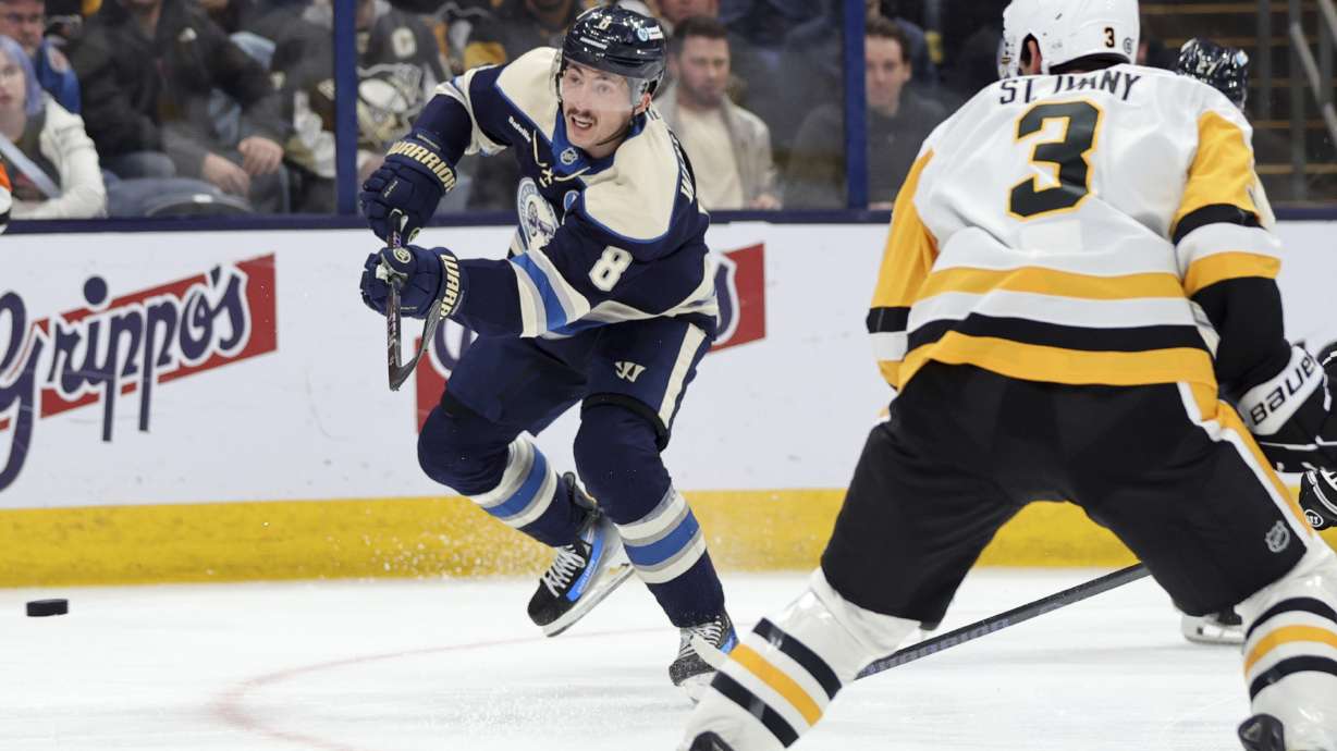Columbus Blue Jackets defenseman Zach Werenski, left, shoots the puck in front of Pittsburgh Penguins defenseman Jack St. Ivany during the second period of an NHL hockey game in Columbus, Ohio, Friday, Nov. 15, 2024.