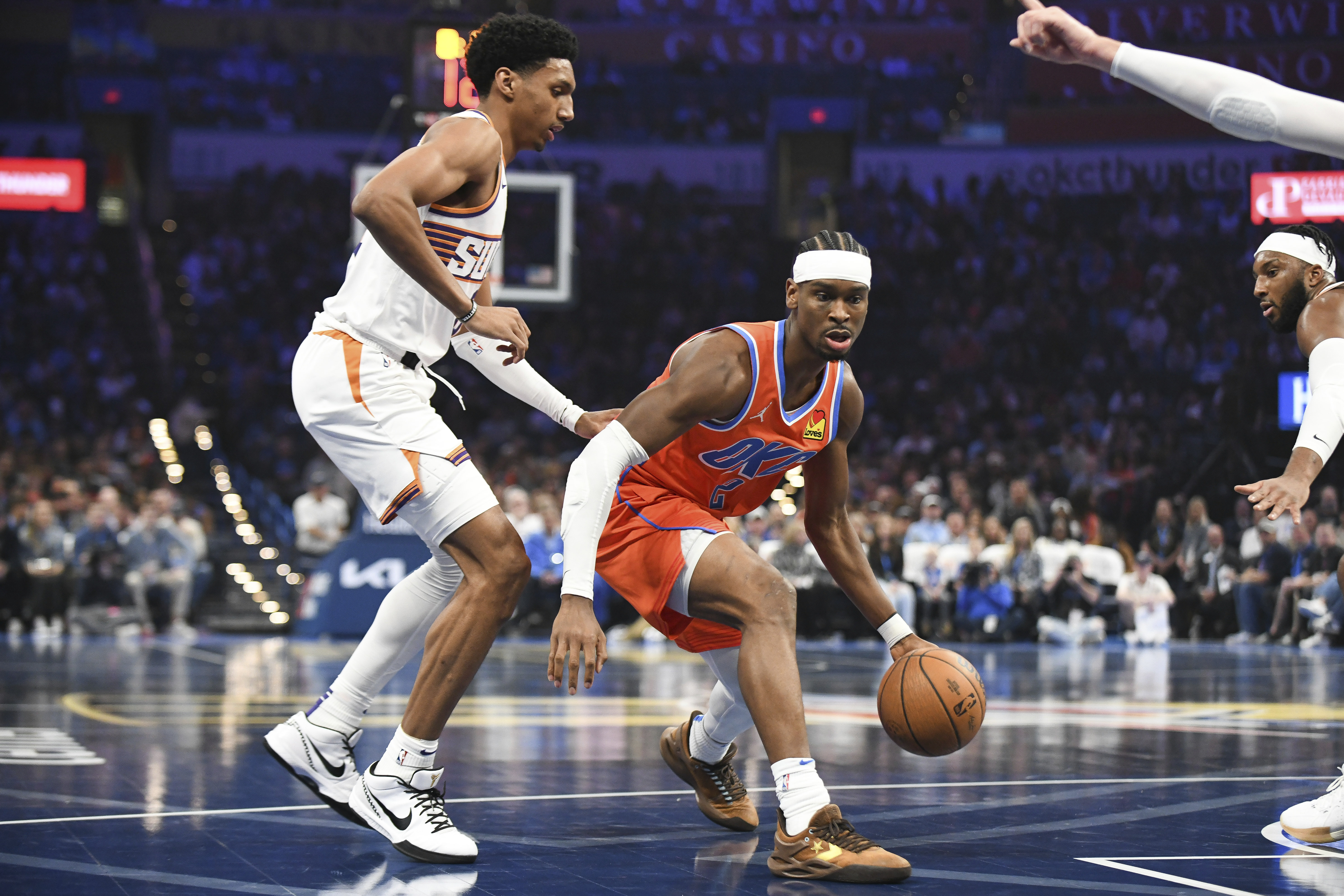 Oklahoma City Thunder guard Shai Gilgeous-Alexander, right, drives past Phoenix Suns forward Ryan Dunn, left, during the first half of an Emirates NBA Cup basketball game, Friday, Nov. 15, 2024, in Oklahoma City.