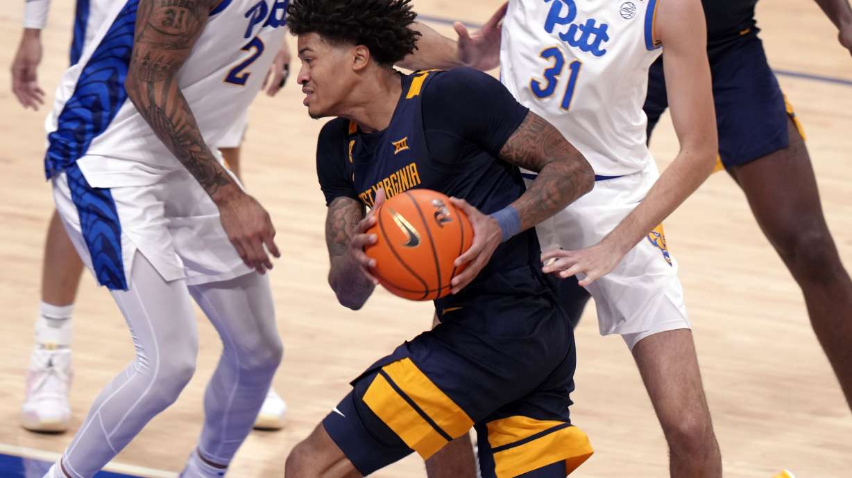 West Virginia's Jonathan Powell, center, is defended by Pittsburgh's Cameron Corhen (2) and Guillermo Diaz Graham (25) during the second half of an NCAA college basketball game Friday, Nov. 15, 2024, in Pittsburgh.