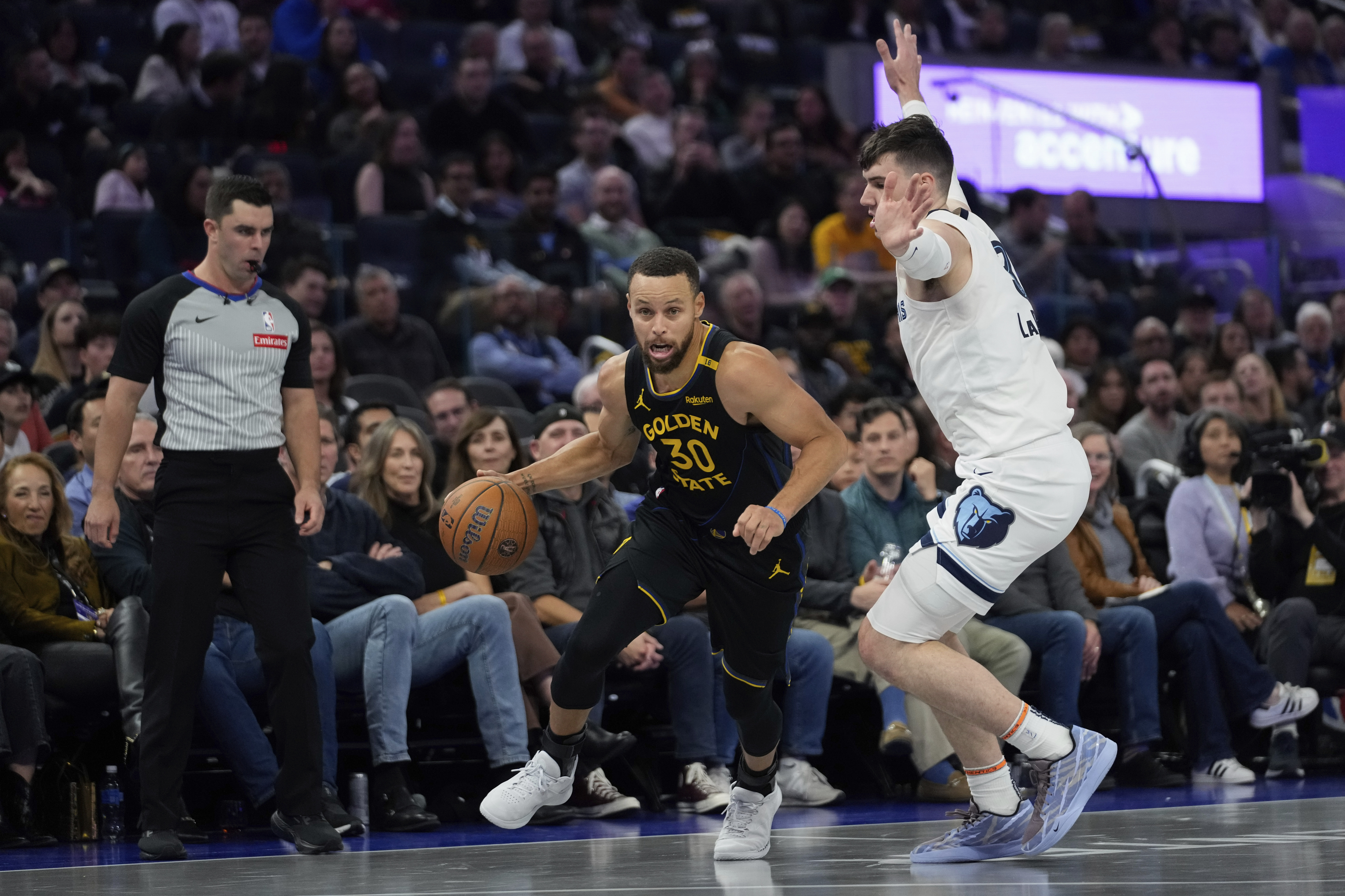 Golden State Warriors guard Stephen Curry (30) moves the ball while defended by Memphis Grizzlies forward Jake LaRavia during the first half of an Emirates NBA Cup basketball game Friday, Nov. 15, 2024, in San Francisco.