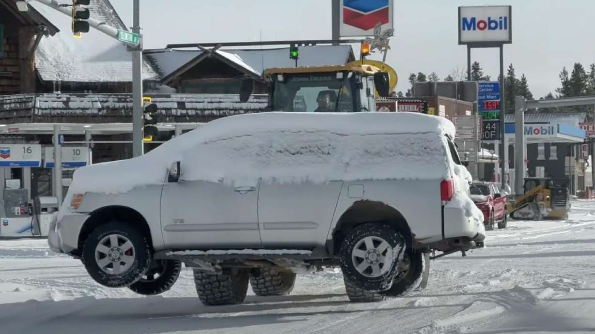 A forklift moves a snowed-in SUV with flat tires in West Yellowstone, Mont.