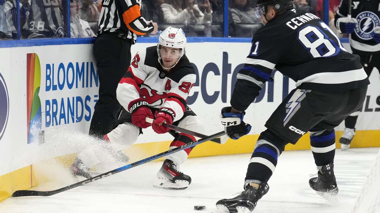 New Jersey Devils center Jack Hughes (86) slips the puck away from Tampa Bay Lightning defenseman Erik Cernak (81) during the first period of an NHL hockey game Saturday, Nov. 16, 2024, in Tampa, Fla.