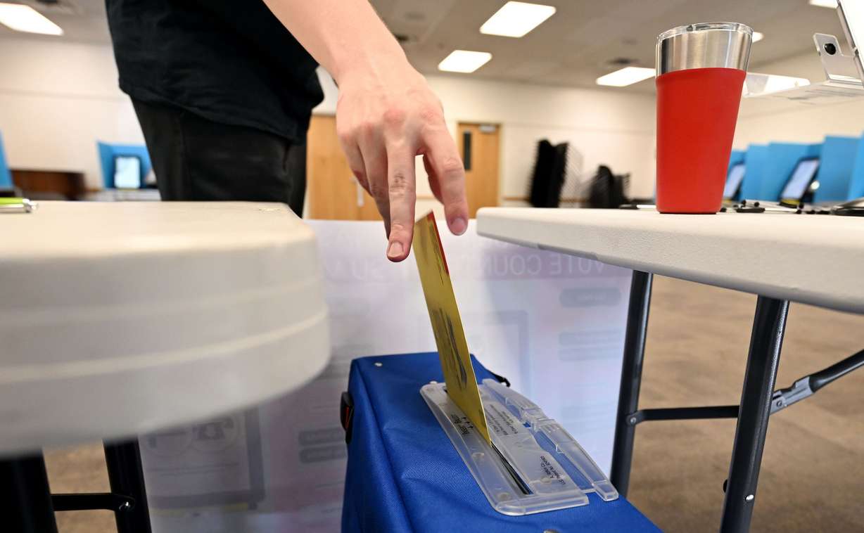 A young man places a ballot into the container as voters turn out to cast their primary votes at the Salt Lake County Library in Sandy on June 25.