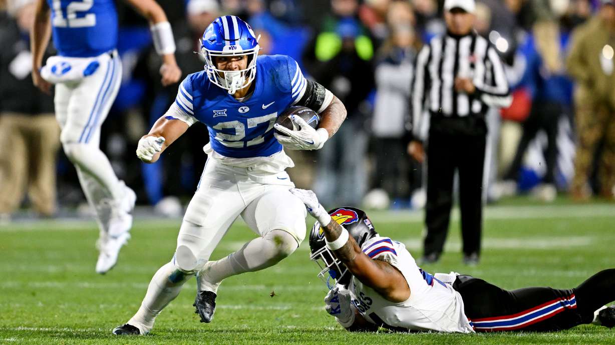 Brigham Young Cougars running back LJ Martin (27) runs out of a tackle attempt by Kansas Jayhawks linebacker Cornell Wheeler (44) as BYU and Kansas play at LaVell Edwards Stadium in Provo on Saturday, Nov. 16, 2024.