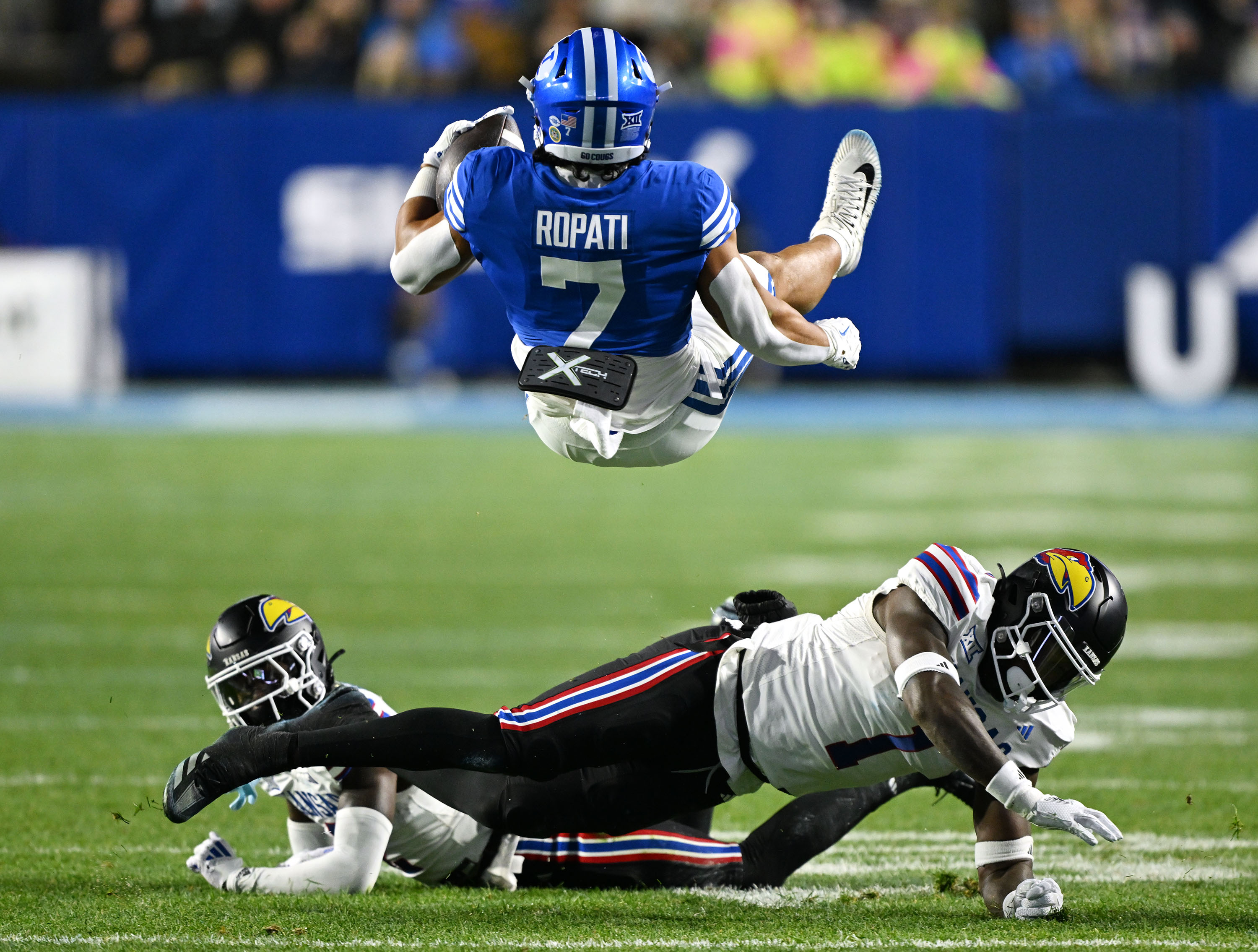 Brigham Young Cougars running back Hinckley Ropati (7) is flipped around after being hit by Kansas Jayhawks linebacker JB Brown (1) as BYU and Kansas play at LaVell Edwards Stadium in Provo on Saturday, Nov. 16, 2024.