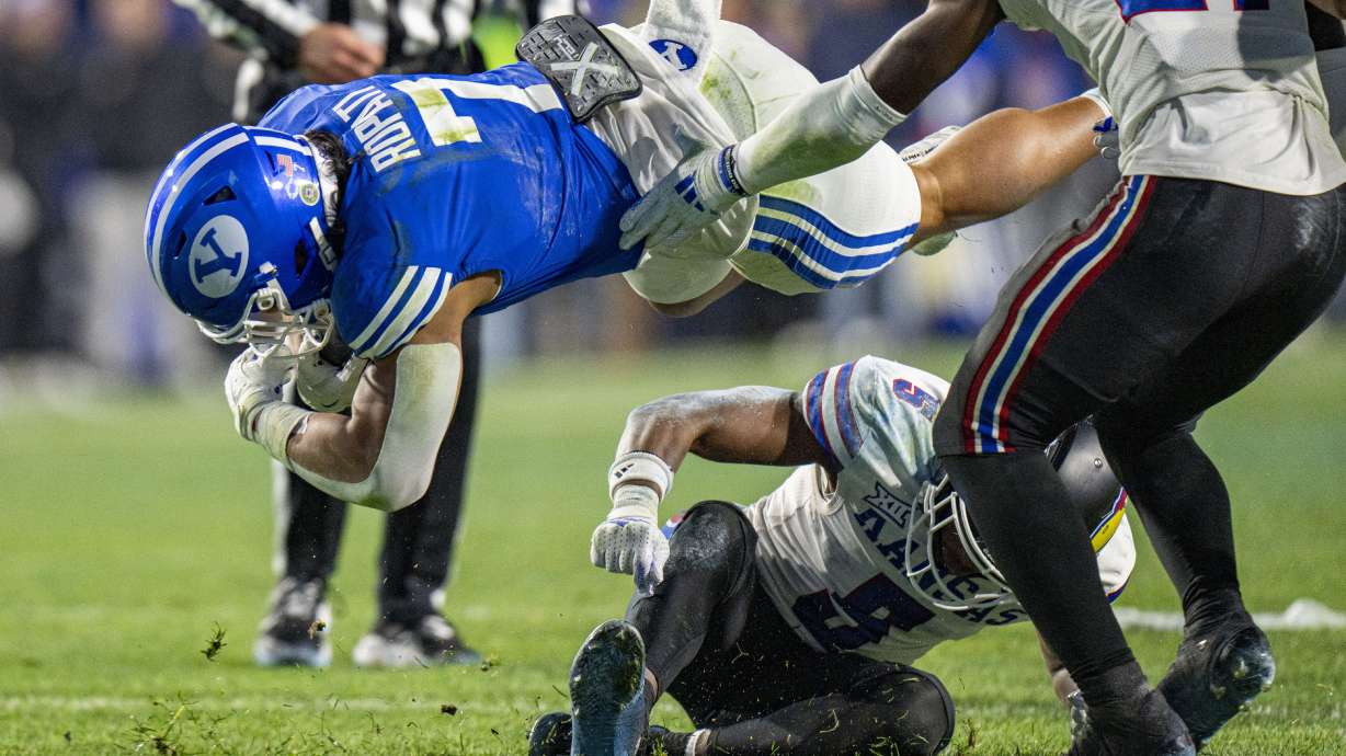 Brigham Young Cougars running back Hinckley Ropati (7) is tripped up by Kansas Jayhawks safety O.J. Burroughs (5) during the first half of an NCAA college football game Saturday, Nov. 16, 2024, in Provo.