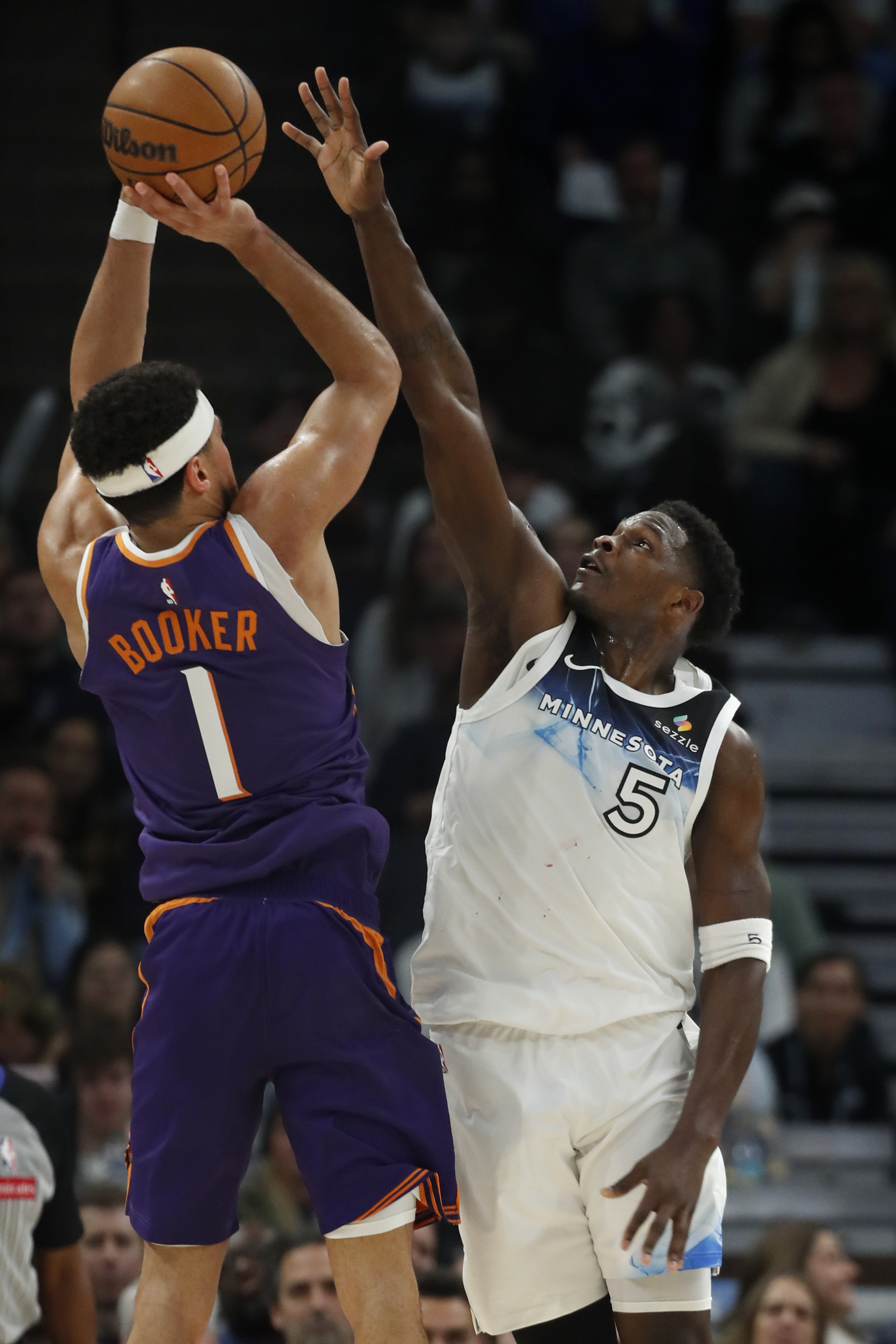 Phoenix Suns guard Devin Booker (1) shoots against Minnesota Timberwolves guard Anthony Edwards (5) in the first quarter of an NBA basketball game Sunday, Nov. 17, 2024, in Minneapolis. 