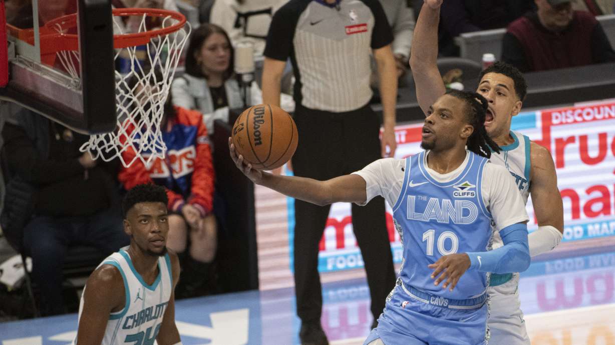 Cleveland Cavaliers' Darius Garland (10) lays in a shot as Charlotte Hornets' Josh Green, right, defends and Hornets' Brandon Miller (24) watches during the first half of an NBA basketball game in Cleveland, Sunday, Nov 17, 2024.