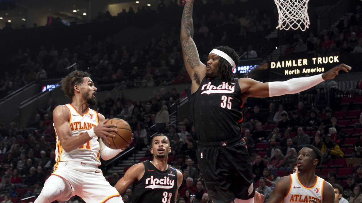Atlanta Hawks guard Trae Young, left, looks to pass the ball against Portland Trail Blazers center Robert Williams III (35) as Trail Blazers forward Toumani Camara (33) defends during the first half of an NBA basketball game in Portland, Ore., Sunday, Nov. 17, 2024.