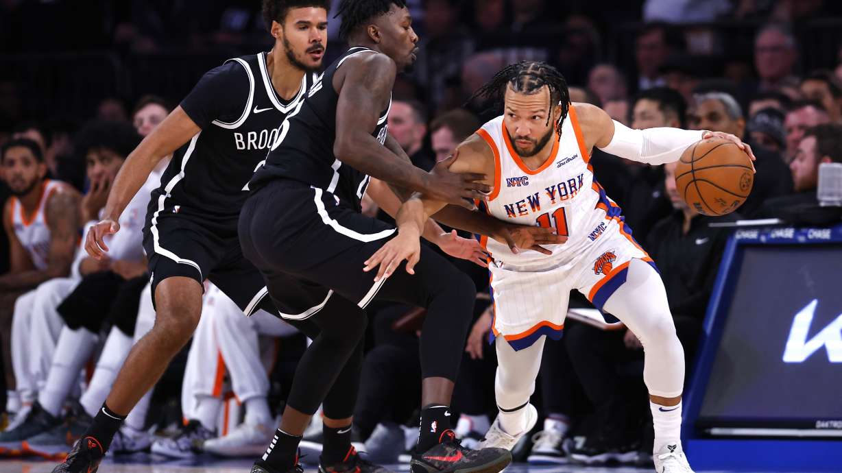 New York Knicks guard Jalen Brunson (11) drives to the basket against Brooklyn Nets forward Dorian Finney-Smith, second from left, and Cam Johnson, left, during the first half of an NBA basketball game, Sunday, Nov. 17, 2024, in New York.