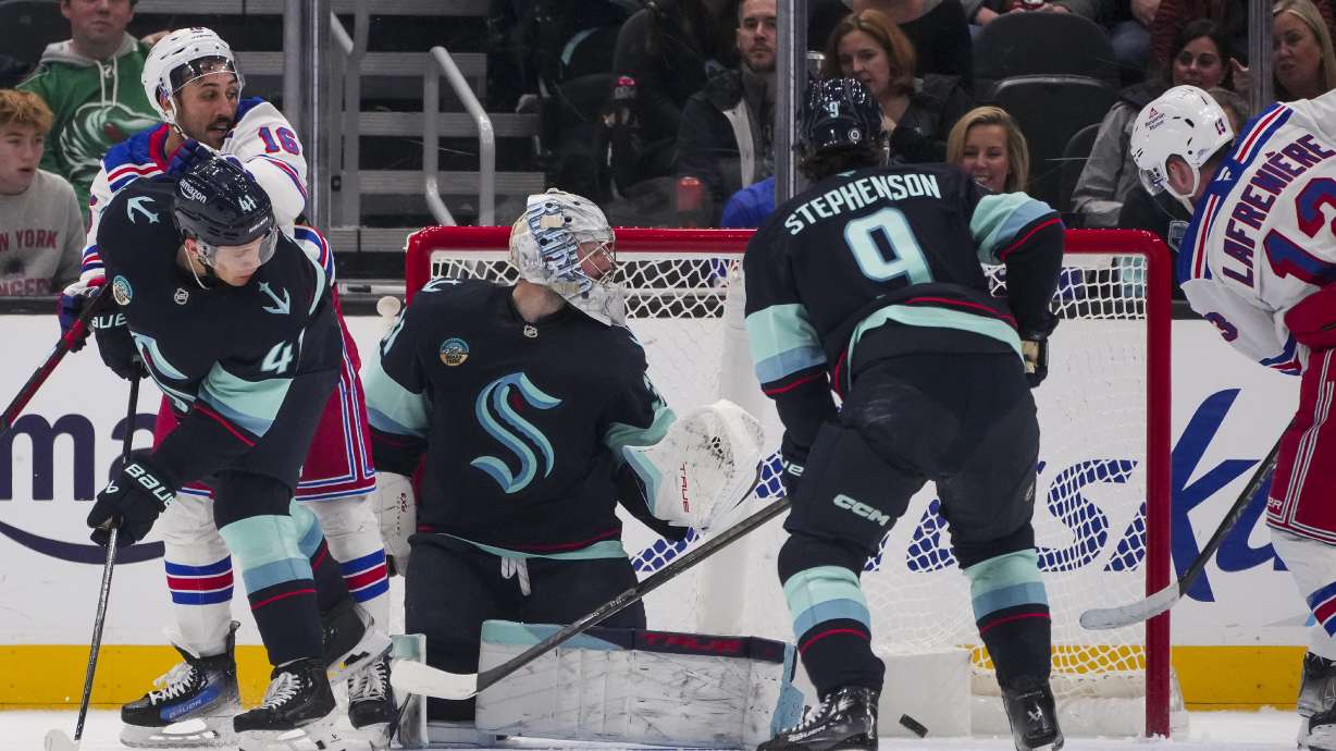 New York Rangers left wing Alexis Lafrenière (13) scores against Seattle Kraken goaltender Philipp Grubauer as center Chandler Stephenson (9), defenseman Ryker Evans (41) and Rangers center Vincent Trocheck (16) look on during the second period of an NHL hockey game Sunday, Nov. 17, 2024, in Seattle.