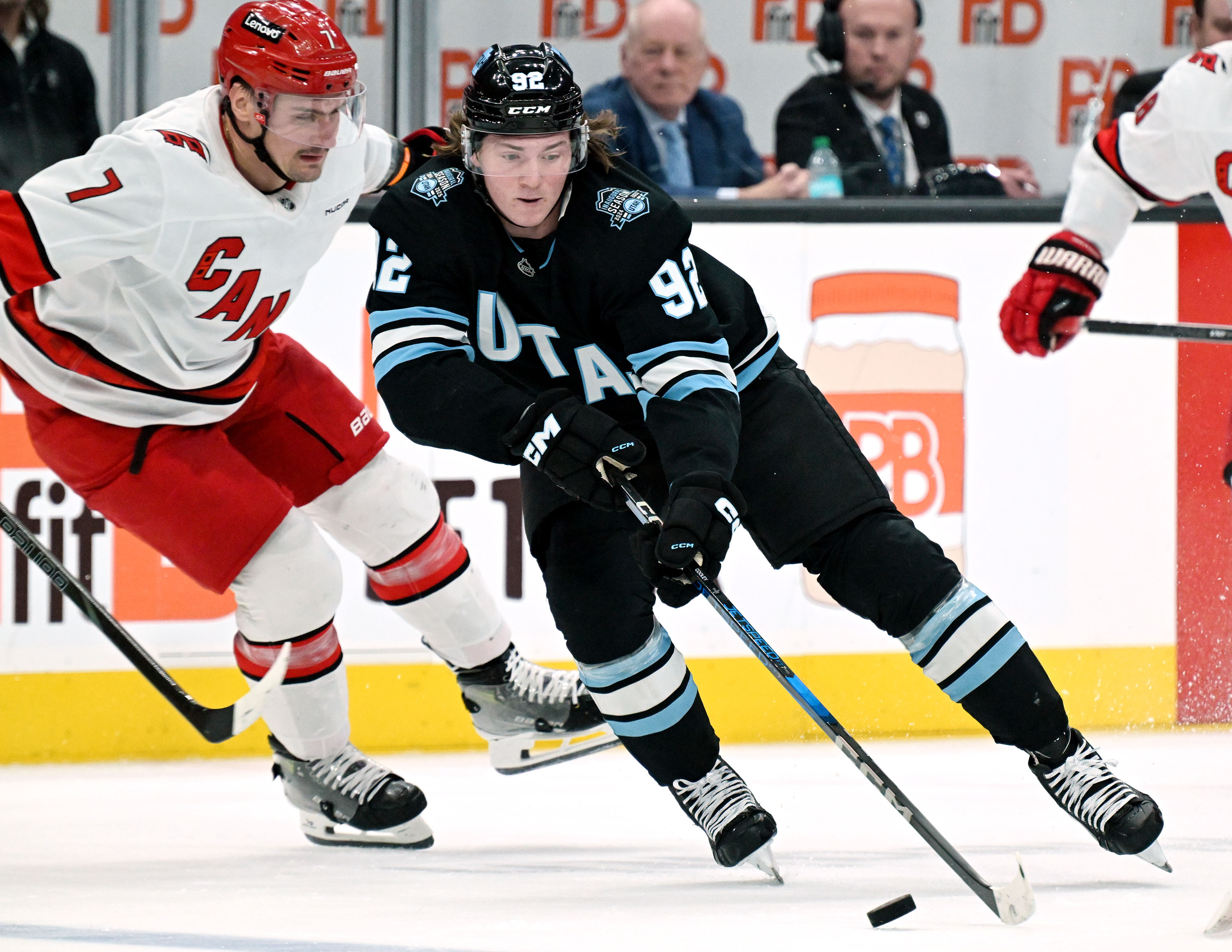 Utah Hockey Club center Logan Cooley (92) skates around Carolina Hurricanes defenseman Dmitry Orlov (7) as the UHC and Hurricanes play at the Delta Center in Salt Lake City on Wednesday, Nov. 13, 2024.