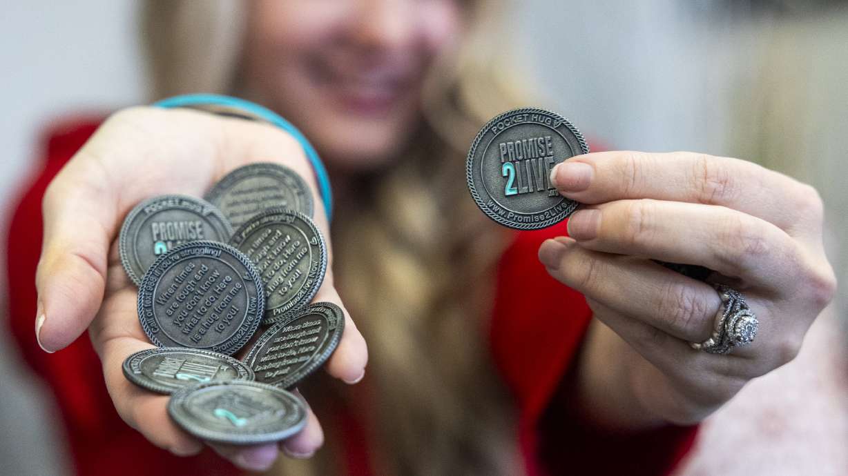 Brandy Vega, founder of Promise2Live, poses with “pocket hug” coins at the Vega Media Studios in Salt Lake City on Monday. Vega started Promise2Live after nearly losing her 14-year-old daughter to suicide in 2021.