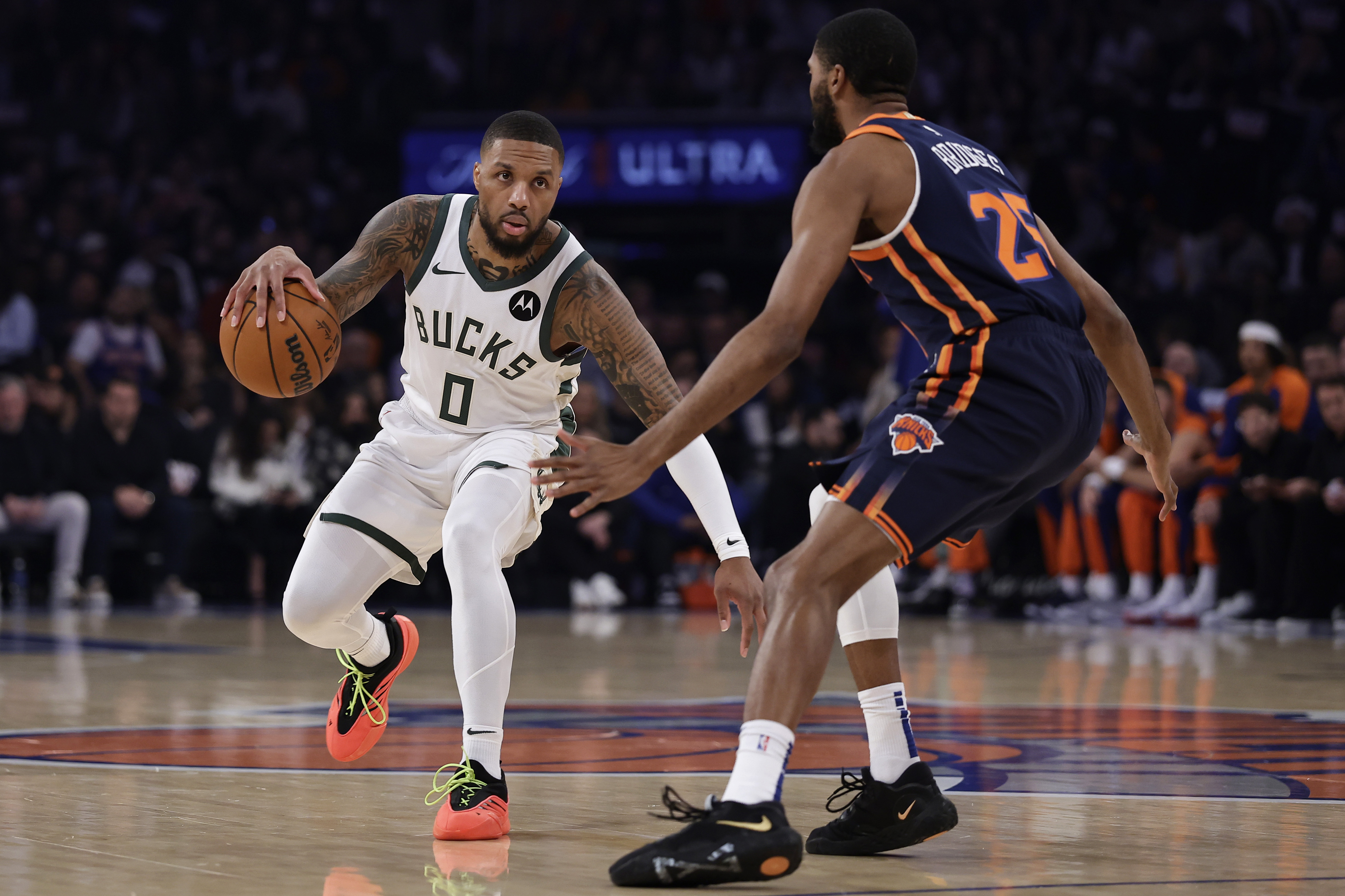 Milwaukee Bucks guard Damian Lillard (0) drives past New York Knicks forward Mikal Bridges during the first half of an NBA basketball game Friday, Nov. 8, 2024, in New York. 