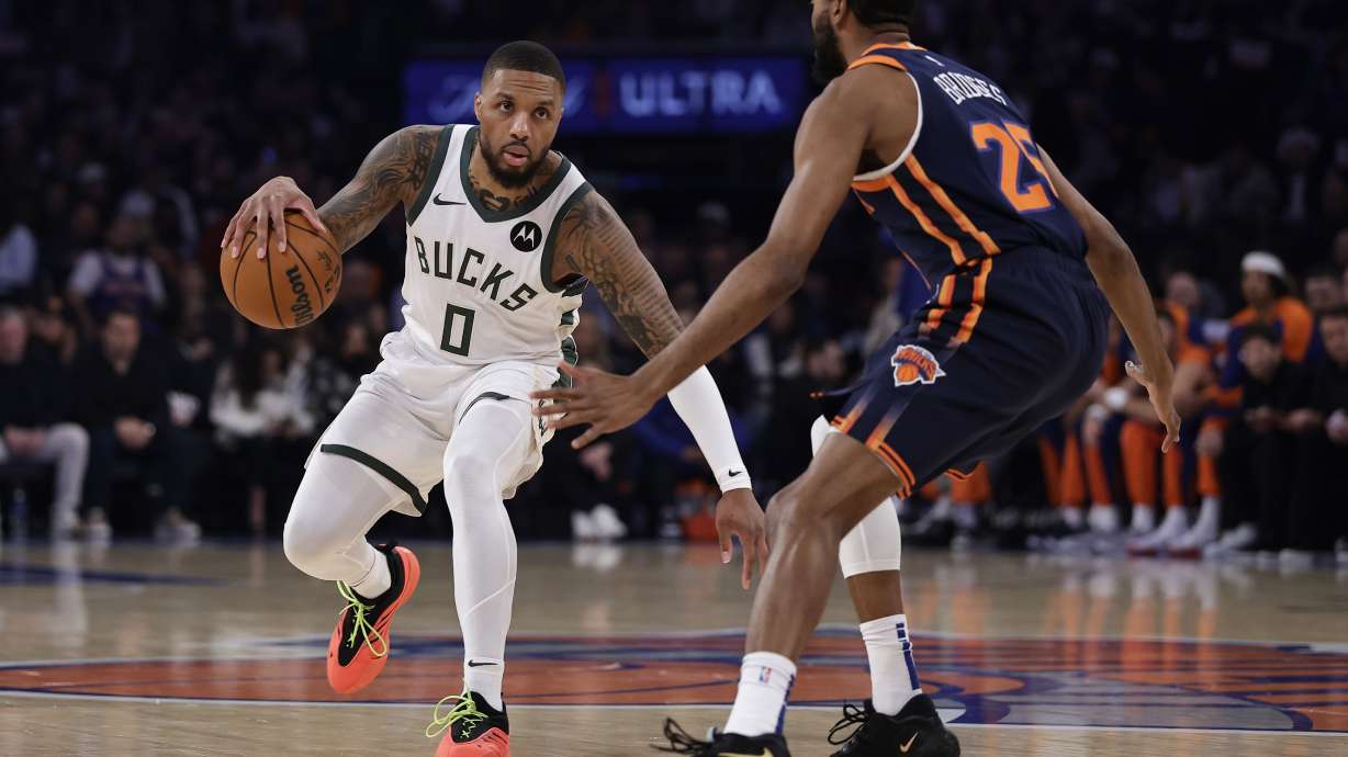 Milwaukee Bucks guard Damian Lillard (0) drives past New York Knicks forward Mikal Bridges during the first half of an NBA basketball game Friday, Nov. 8, 2024, in New York.
