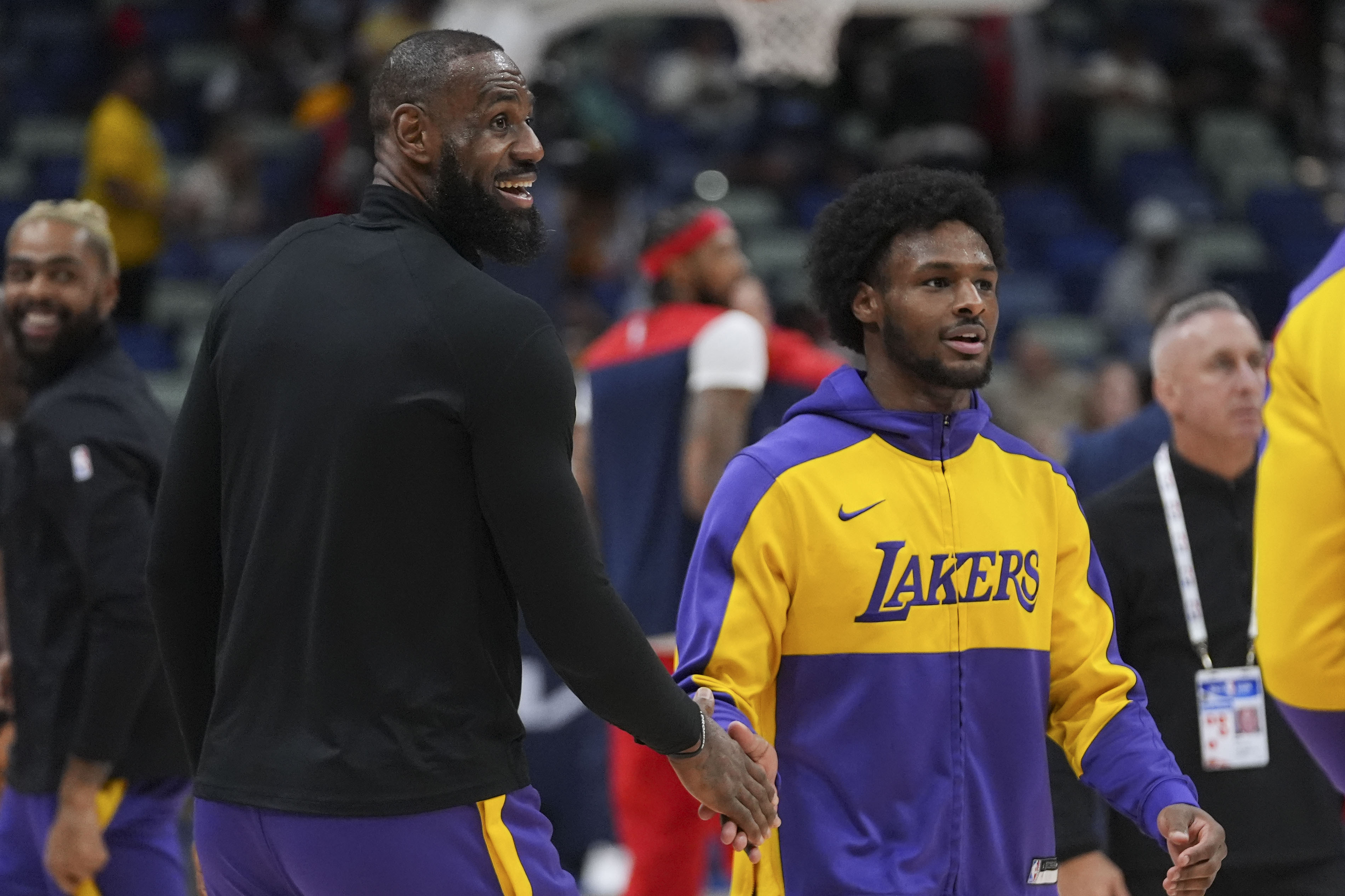 Los Angeles Lakers forward LeBron James greets his son guard Bronny James, right during warm-ups before an NBA basketball game against the New Orleans Pelicans in New Orleans, Saturday, Nov. 16, 2024.