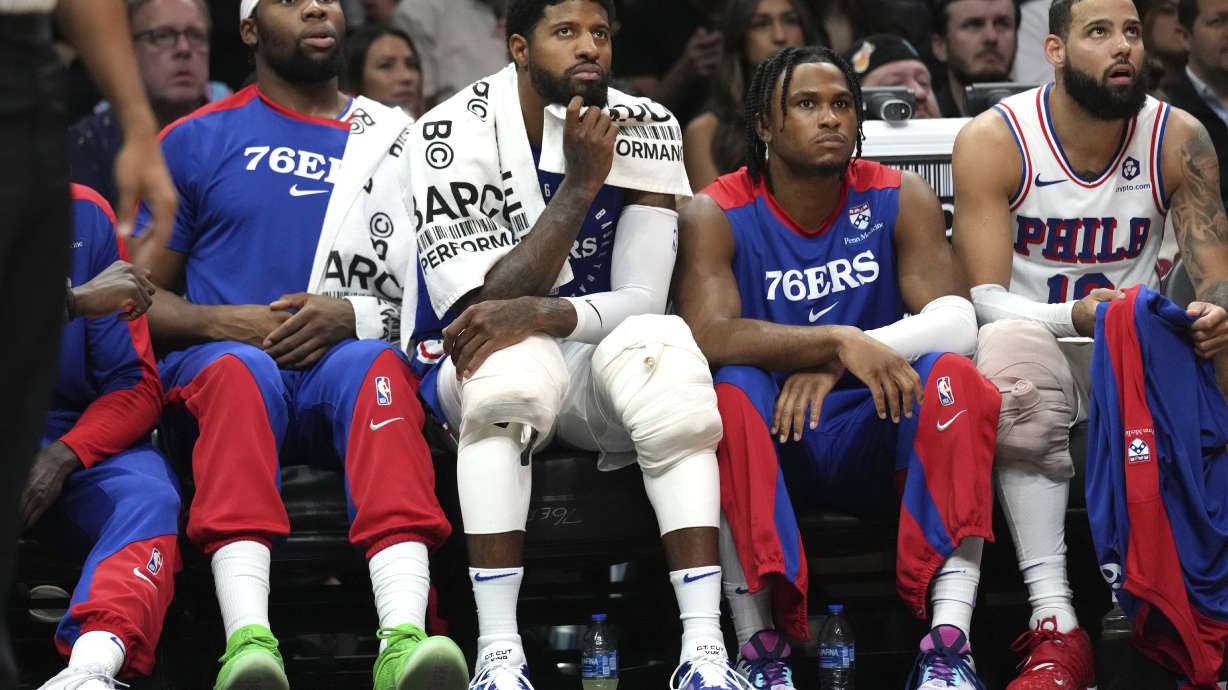 Philadelphia 76ers forward Paul George, second from left, and forward Caleb Martin, right, watch from the bench during the first half of an NBA basketball game against the Miami Heat, Monday, Nov. 18, 2024, in Miami.