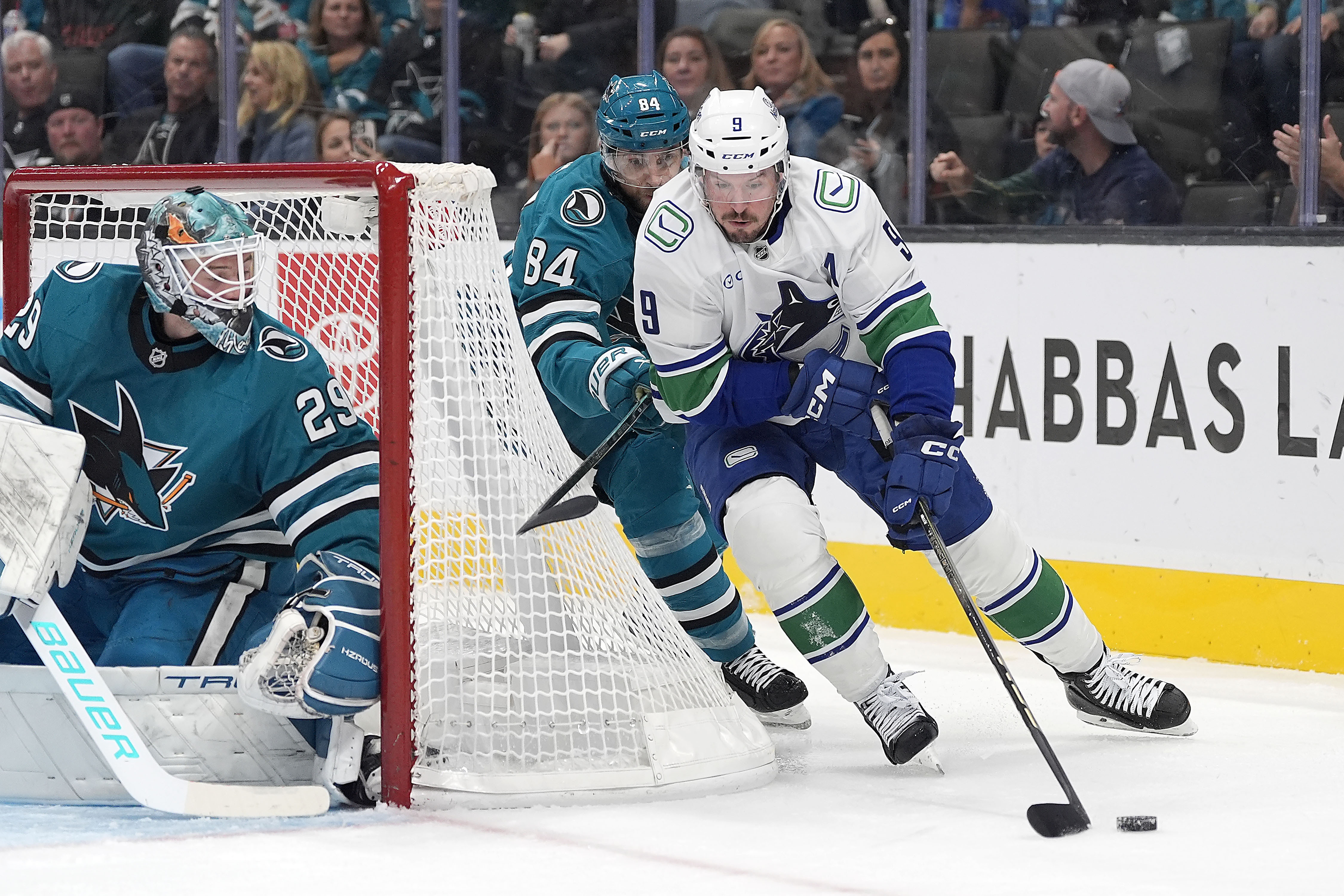 Vancouver Canucks center J.T. Miller (9) skates the puck past San Jose Sharks defenseman Jan Rutta (84) as goaltender Mackenzie Blackwood (29) looks on during the second period of an NHL hockey game in San Jose, Calif., Saturday, Nov. 2, 2024. 