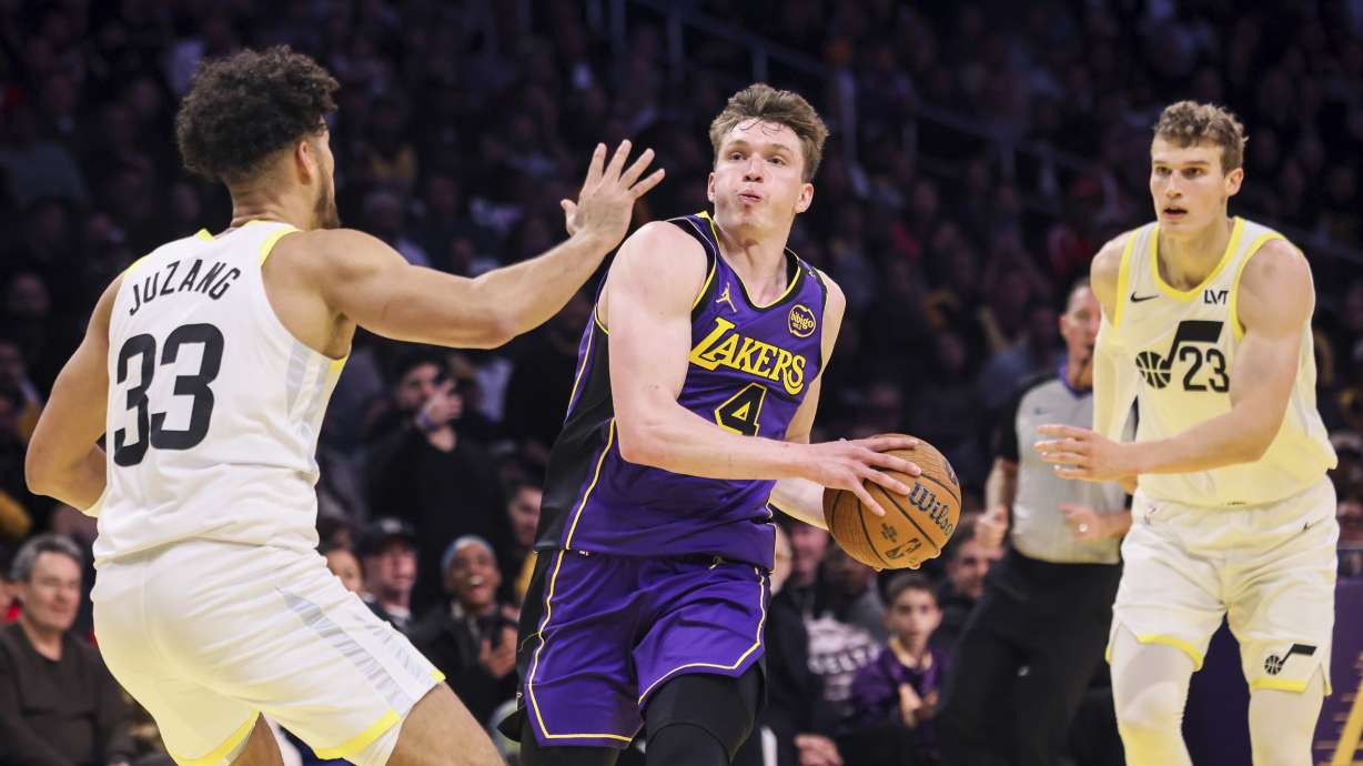 Los Angeles Lakers guard Dalton Knecht, center, dribbles past Utah Jazz forward-center Lauri Markkanen, right, in an attempt to scores against guard Johnny Juzang during the second half of an Emirates NBA Cup basketball game, Tuesday, Nov. 19, 2024, in Los Angeles.