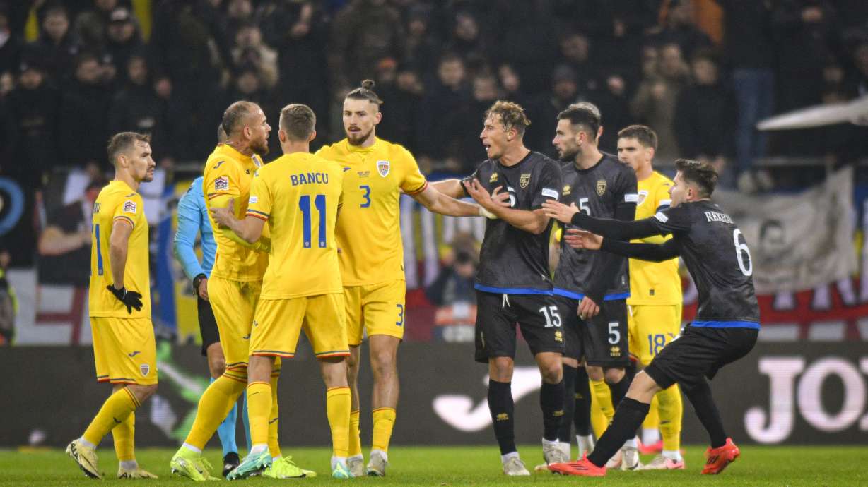 Romania's Radu Dragusin, center, breaks up a scuffle between Romania's Denis Alibec, left, and Kosovo's Mergim Vojvoda during the UEFA Nations League soccer match between Romania and Kosovo was suspended at the National Arena stadium in Bucharest, Romania, Saturday, Nov. 16, 2024.
