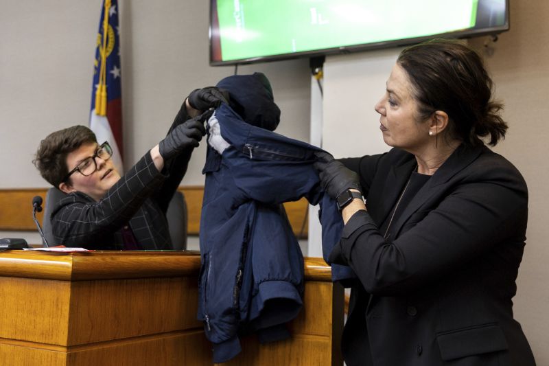 Witness Katrina Ostapovicz, left, a crime lab scientist with the Georgia Bureau of Investigation, and prosector Sheila Ross hold a jacket allegedly worn by defendant Jose Ibarra as Ostapovicz testifies during Ibarra's trial at the Athens-Clarke County Superior Court, Tuesday in Athens, Ga.