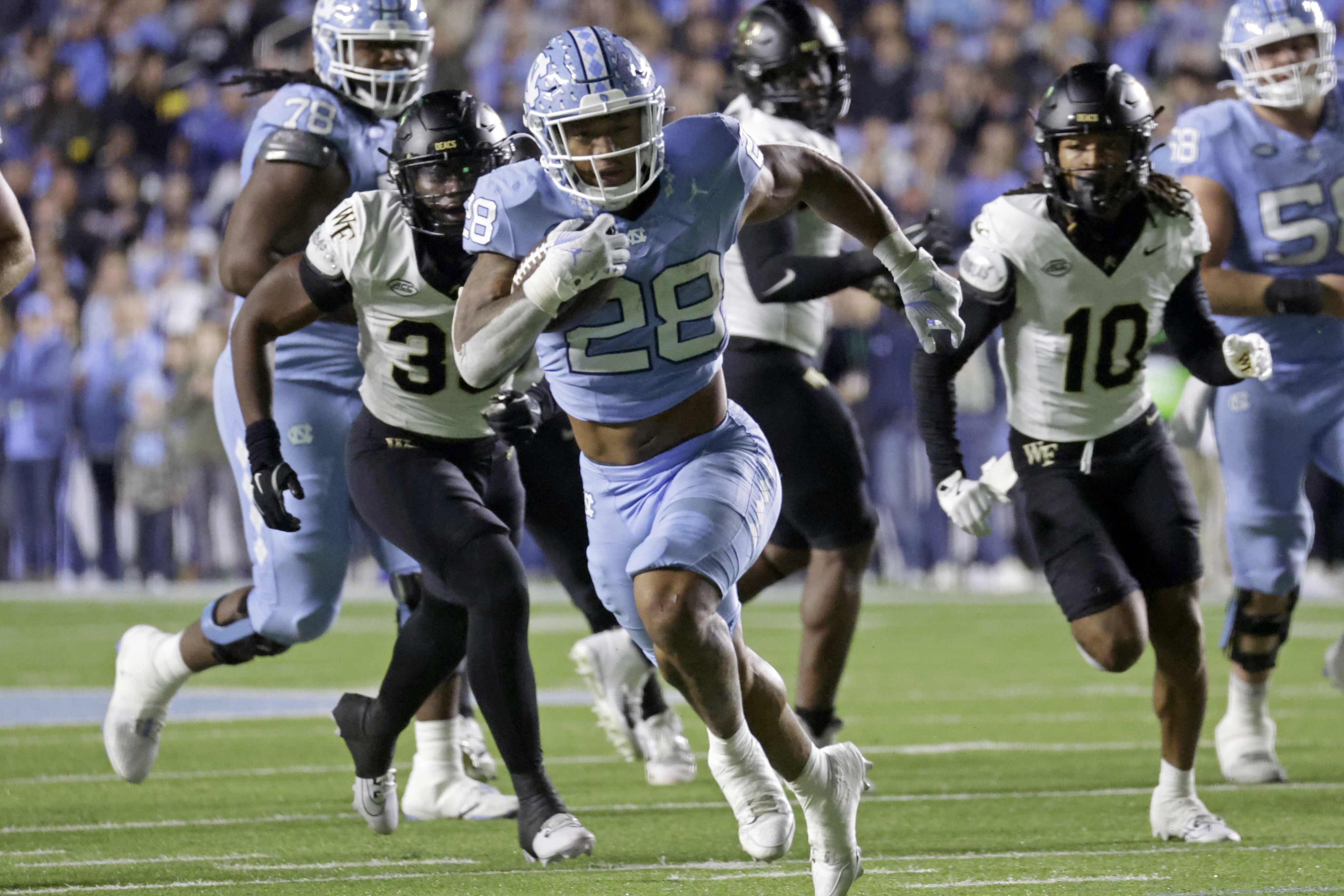 North Carolina running back Omarion Hampton (28) runs past Wake Forest linebacker Aiden Hall and defensive back C'Darius Kelley (10) during the first half of an NCAA college football game Saturday, Nov. 16, 2024, in Chapel Hill, N.C.