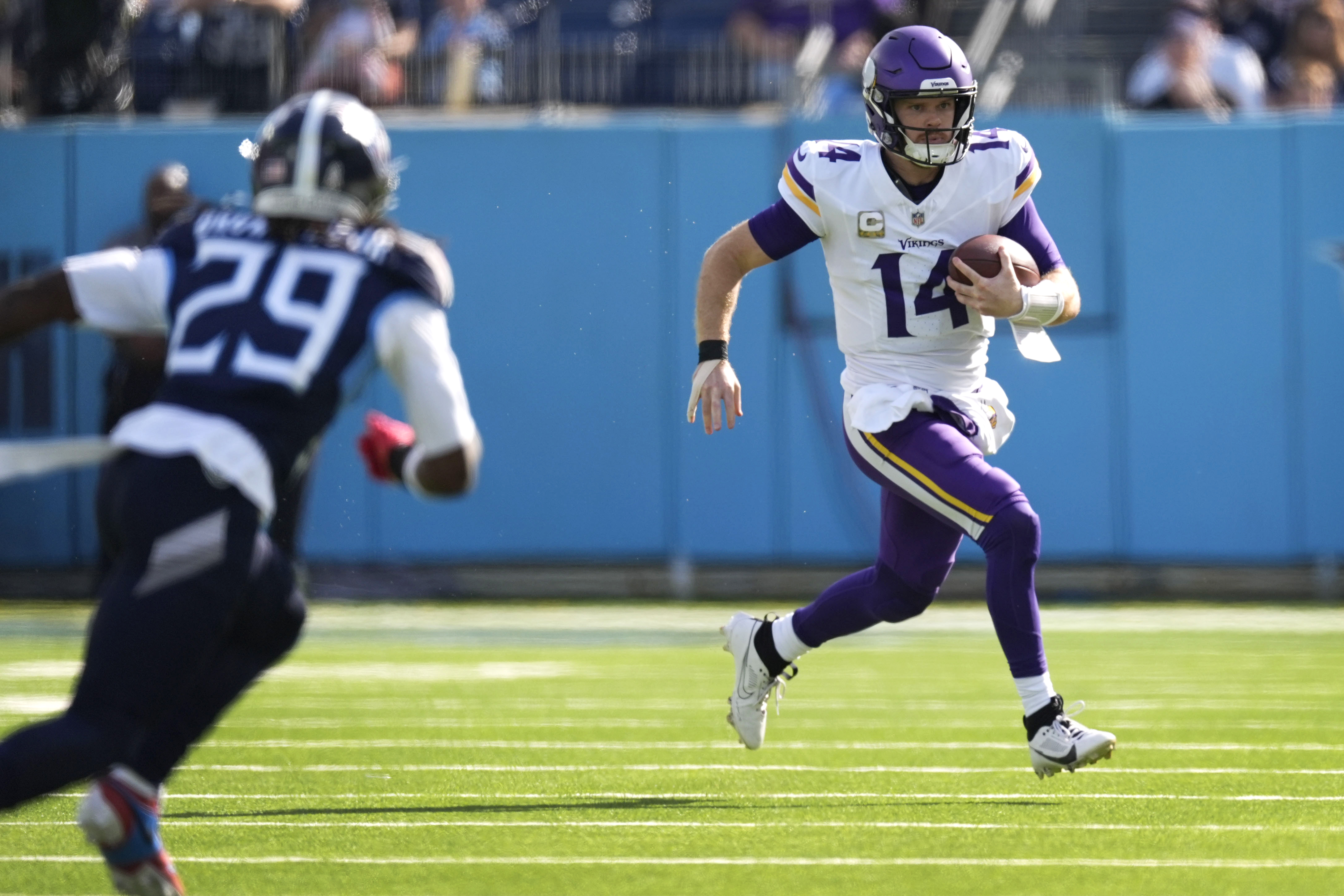 Minnesota Vikings quarterback Sam Darnold (14) scrambles up field ahead of Tennessee Titans cornerback Jarvis Brownlee Jr. (29) during the first half of an NFL football game, Sunday, Nov. 17, 2024, in Nashville, Tenn.