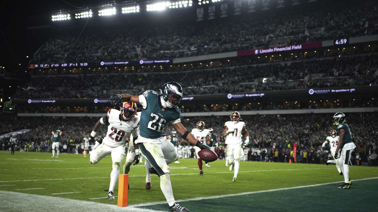 Philadelphia Eagles running back Saquon Barkley (26) scores past Washington Commanders safety Quan Martin (20) during the second half of an NFL football game against the Washington Commanders Thursday, Nov. 14, 2024, in Philadelphia.