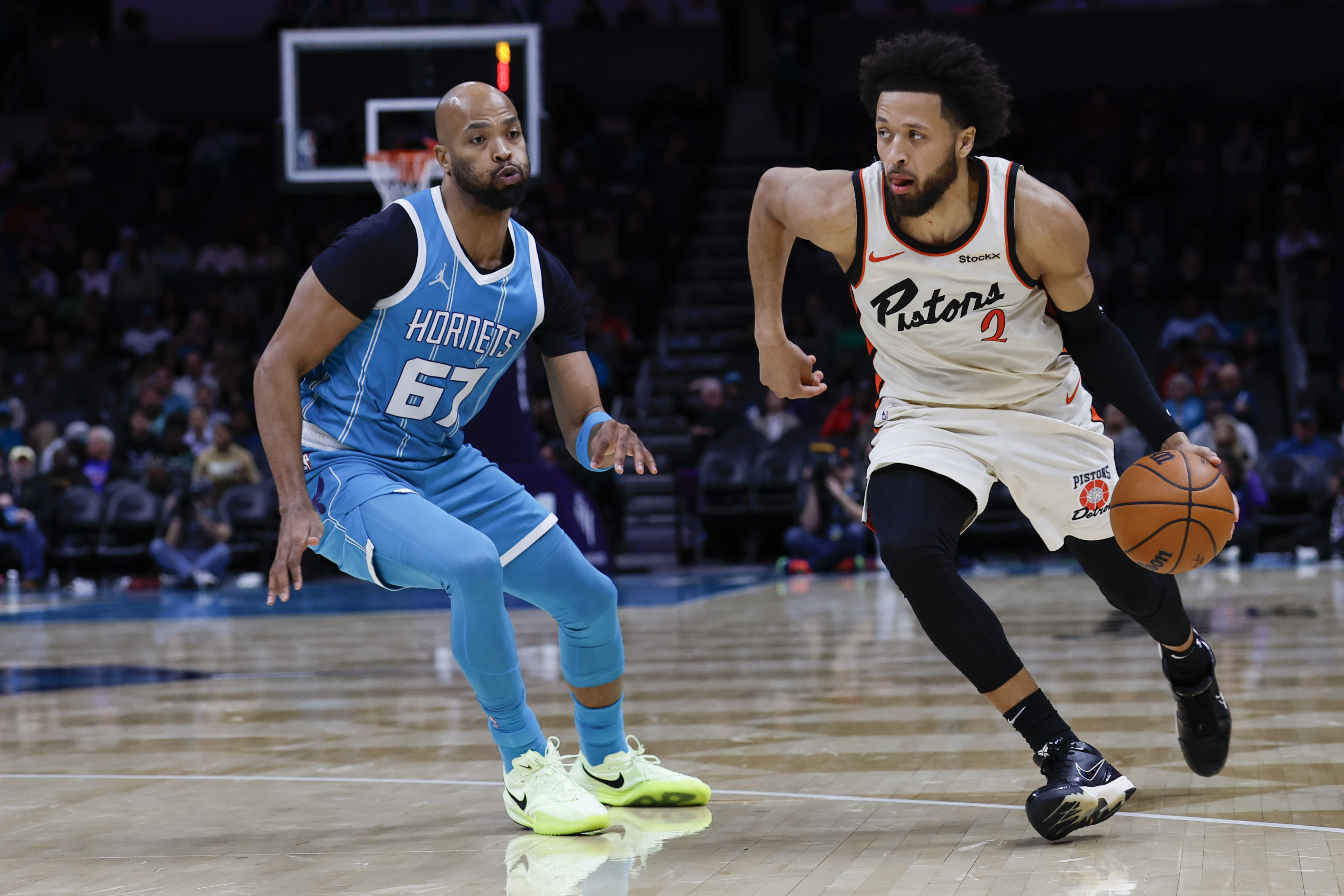 Detroit Pistons guard Cade Cunningham, right, brings the ball upcourt against Charlotte Hornets forward Taj Gibson, left, during the second half of an NBA basketball game in Charlotte, N.C., Thursday, Nov. 21, 2024.